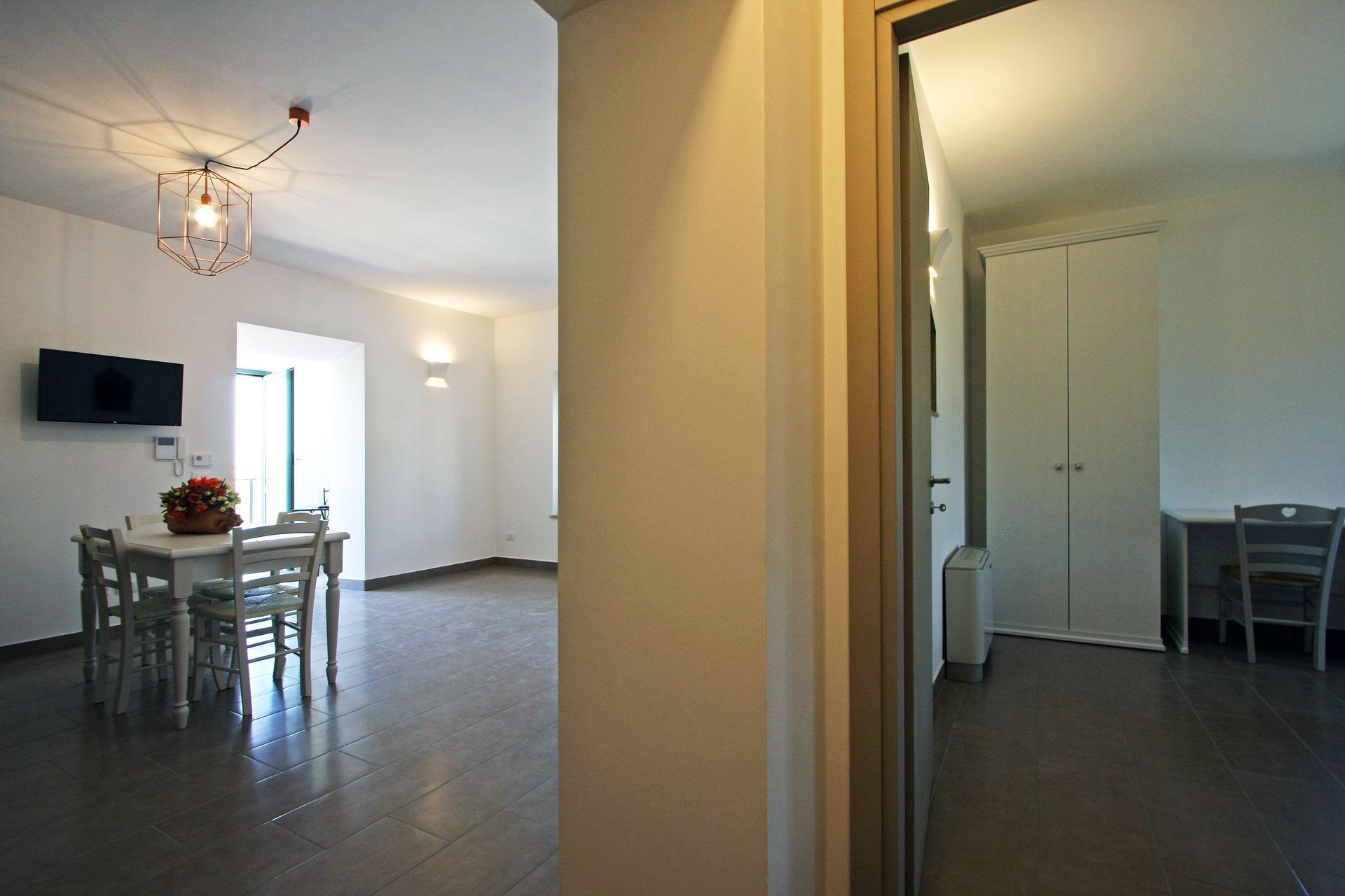 Vista interna di una sala da pranzo bianca e di una porta che si apre