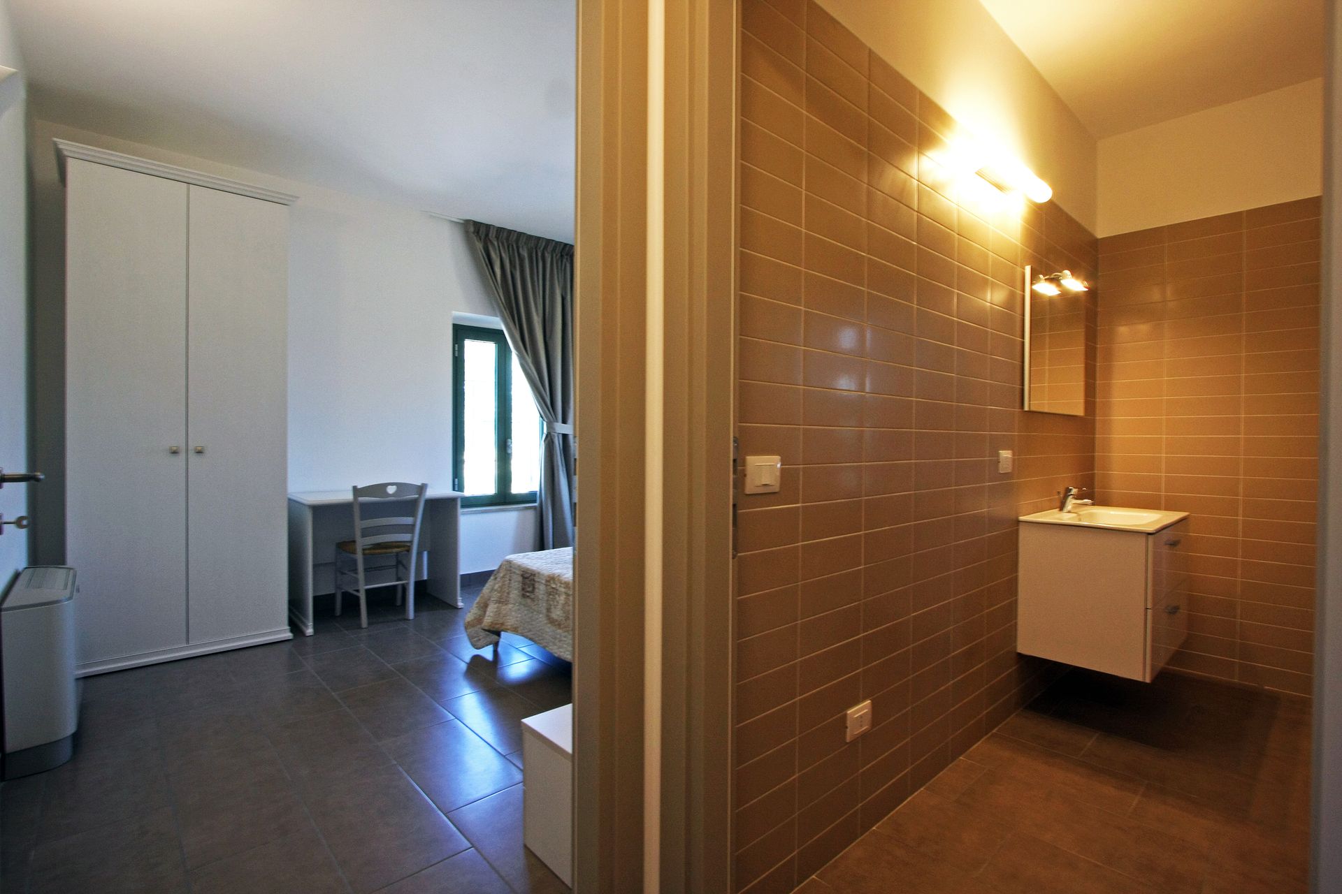 Una vista interna mostra una camera da letto con armadio e scrivania bianchi