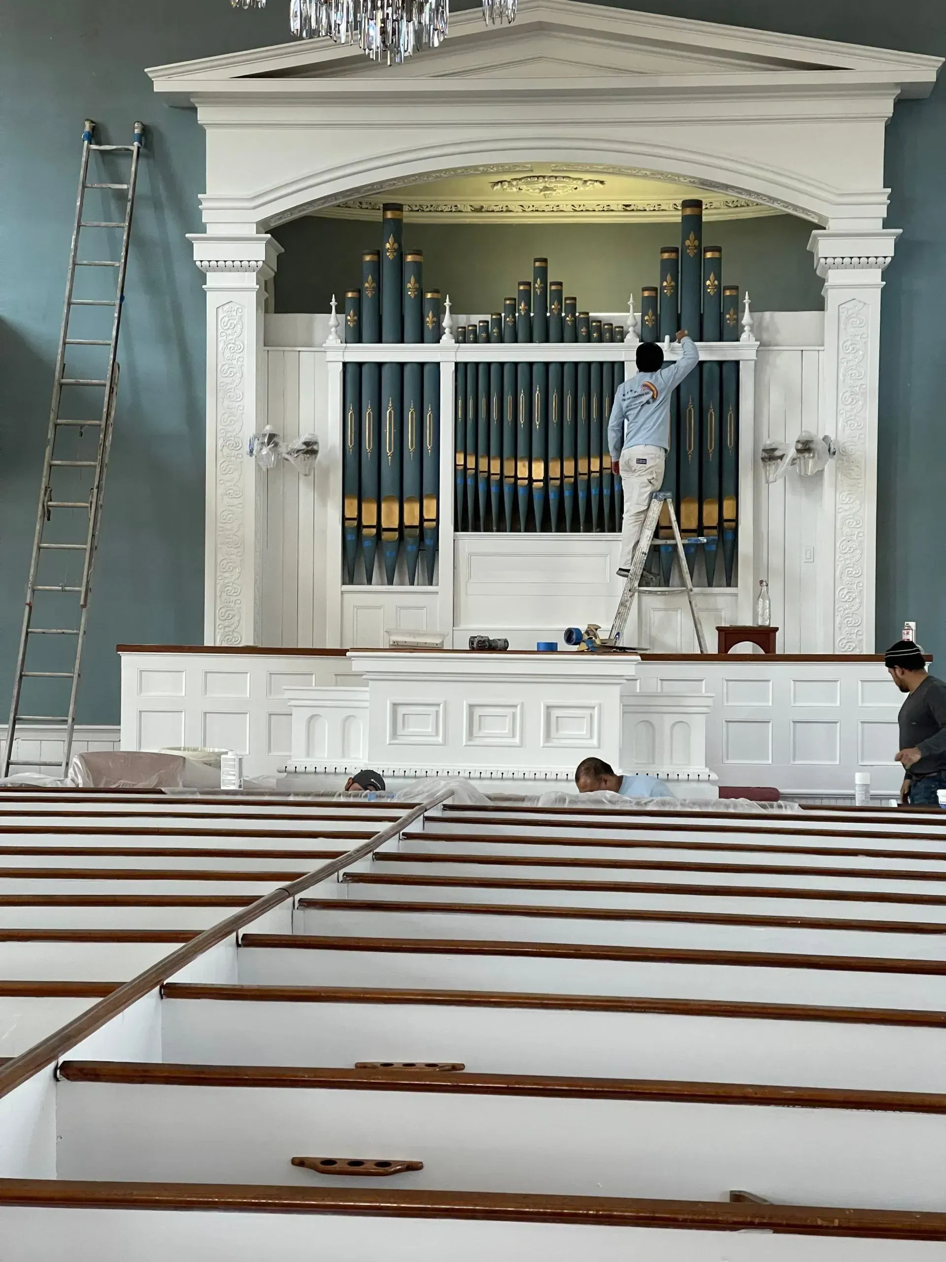 A man on a ladder paints a church organ