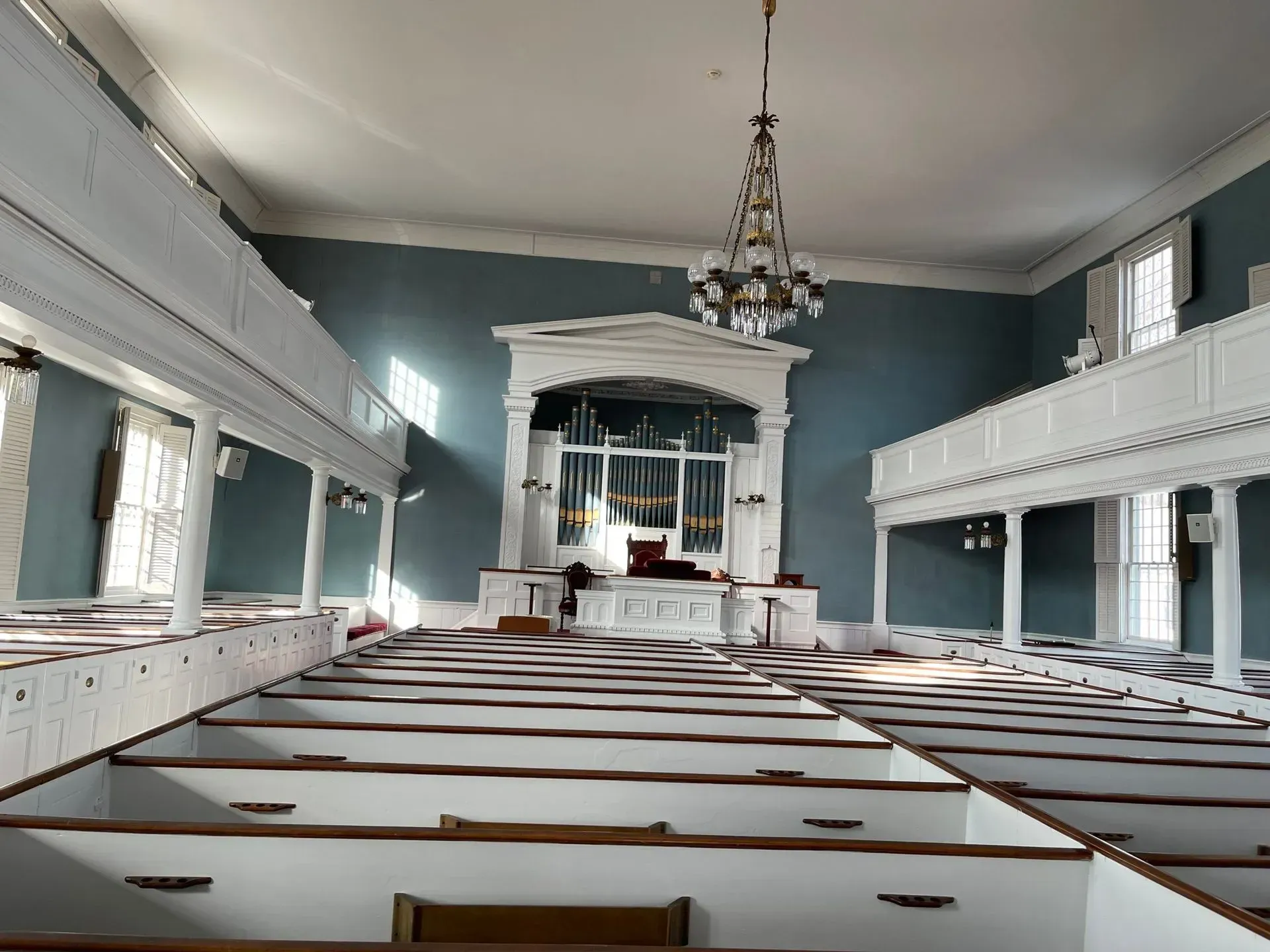 The inside of a church with blue walls and white benches