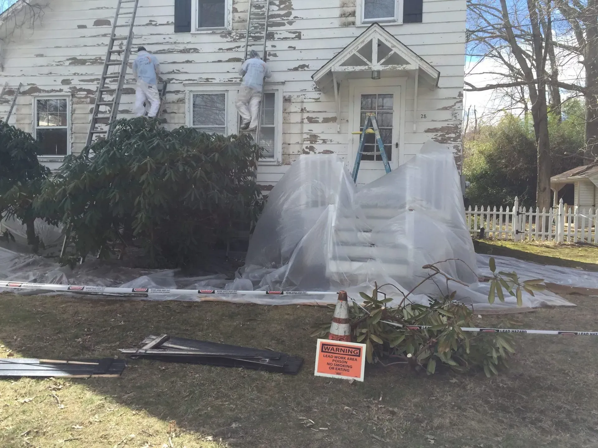 Two men are painting the side of a white house