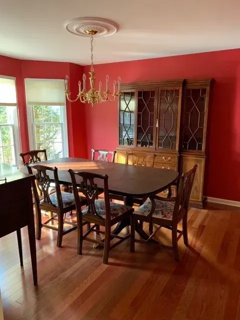 A dining room with red walls and a table and chairs