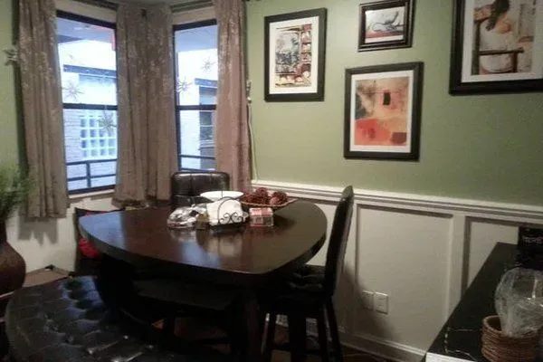 A dining room with a table and chairs and pictures on the wall