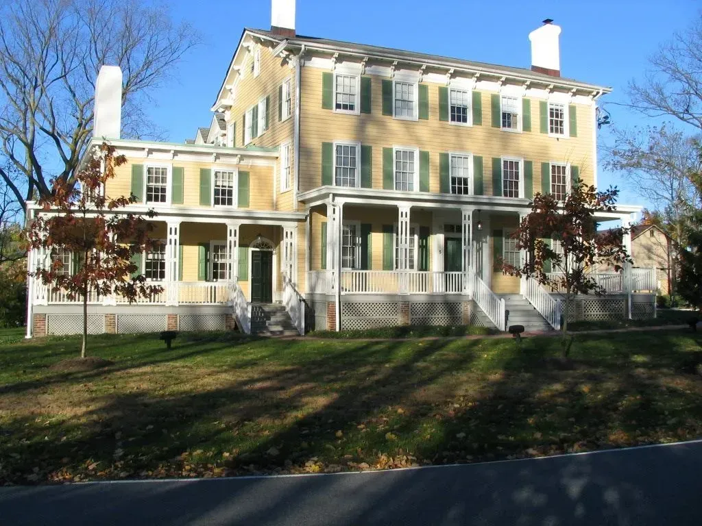A large yellow house with green shutters and a large porch