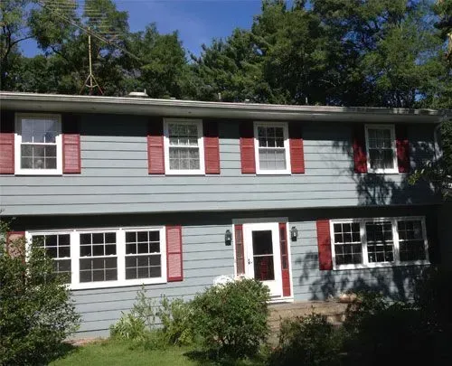 A blue house with red shutters and white windows
