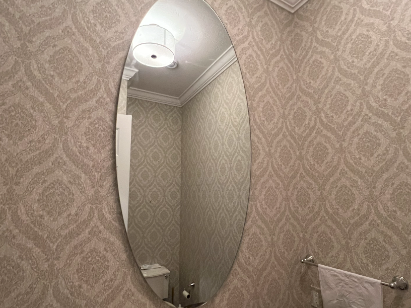 A bathroom with a large oval mirror on the wall.