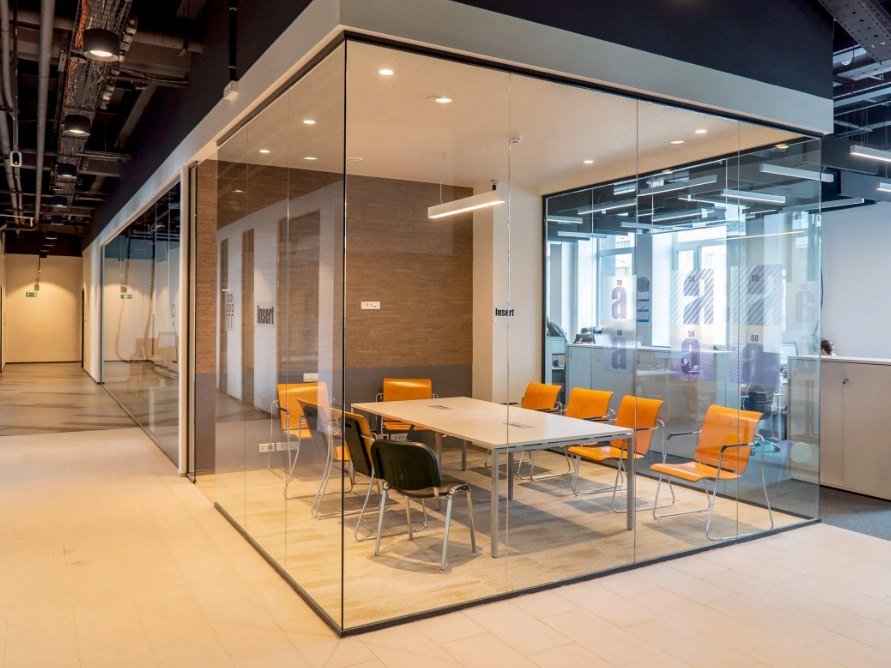A conference room with a glass wall and a table and chairs.
