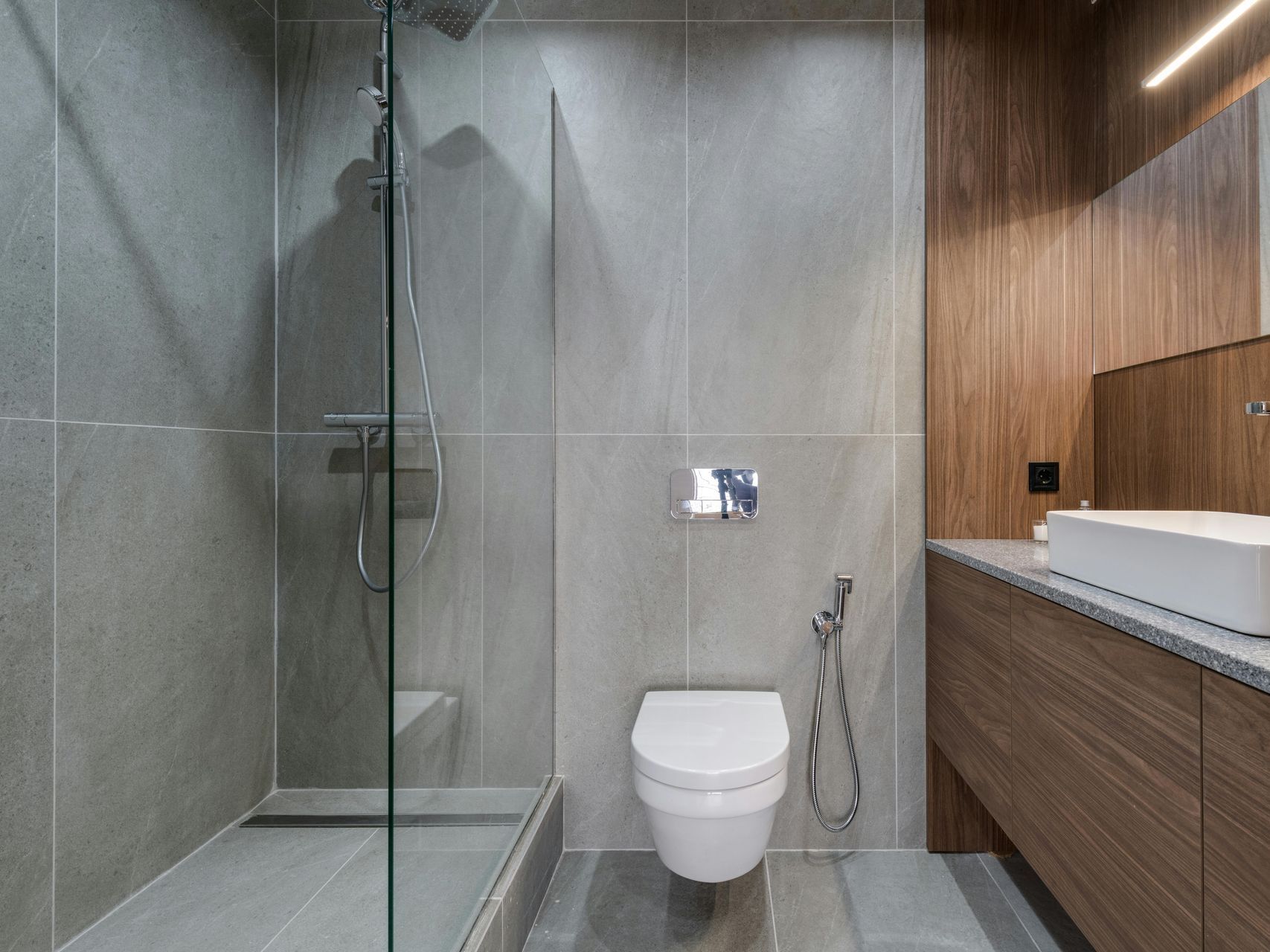 A bathroom with a toilet , sink and walk in shower.