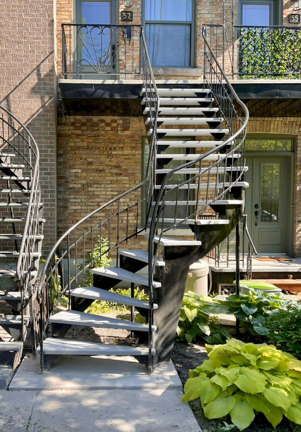 Un escalier en colimaçon mène au deuxième étage d'un immeuble en briques.