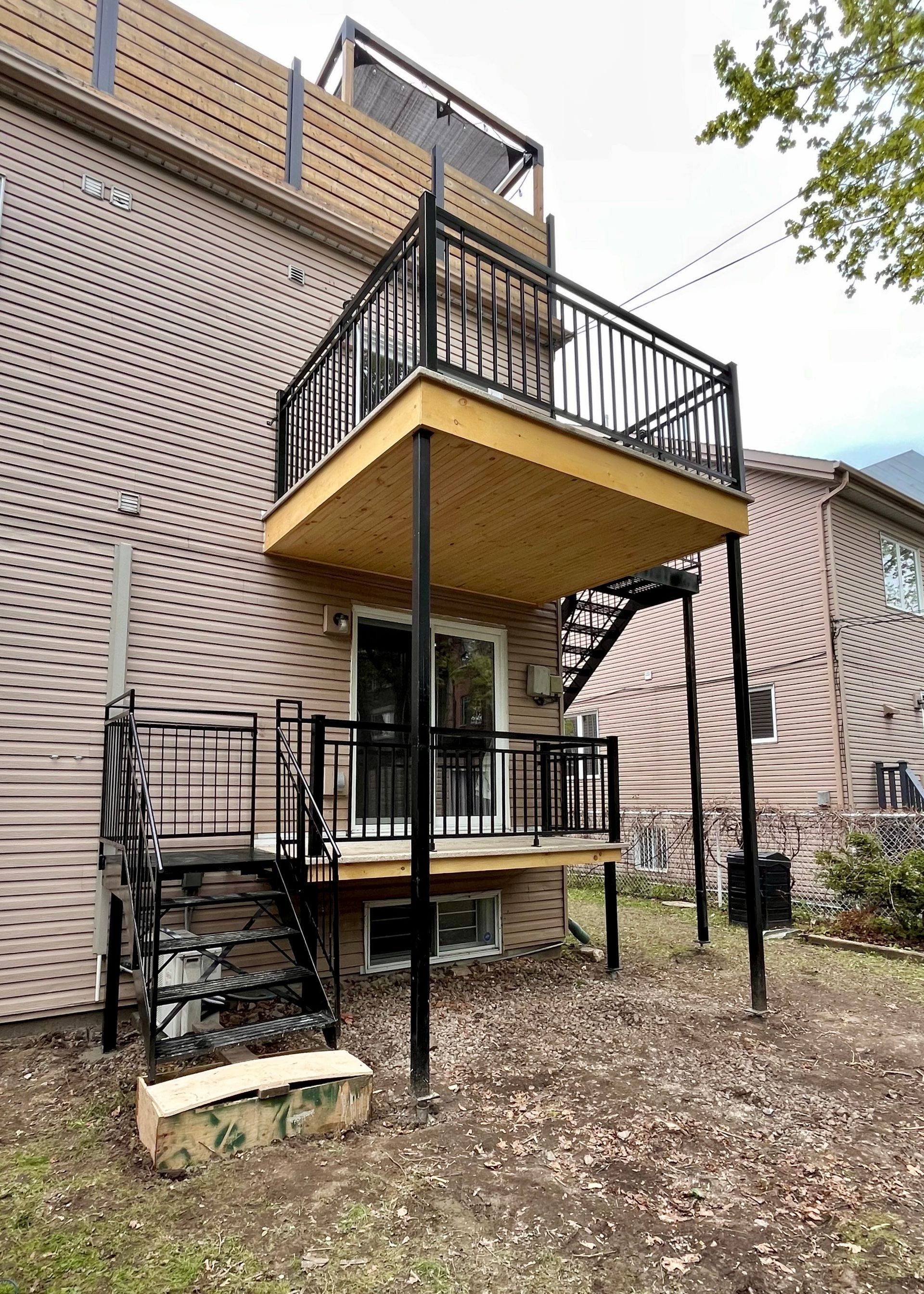L'arrière d'une maison avec un balcon et des escaliers.
