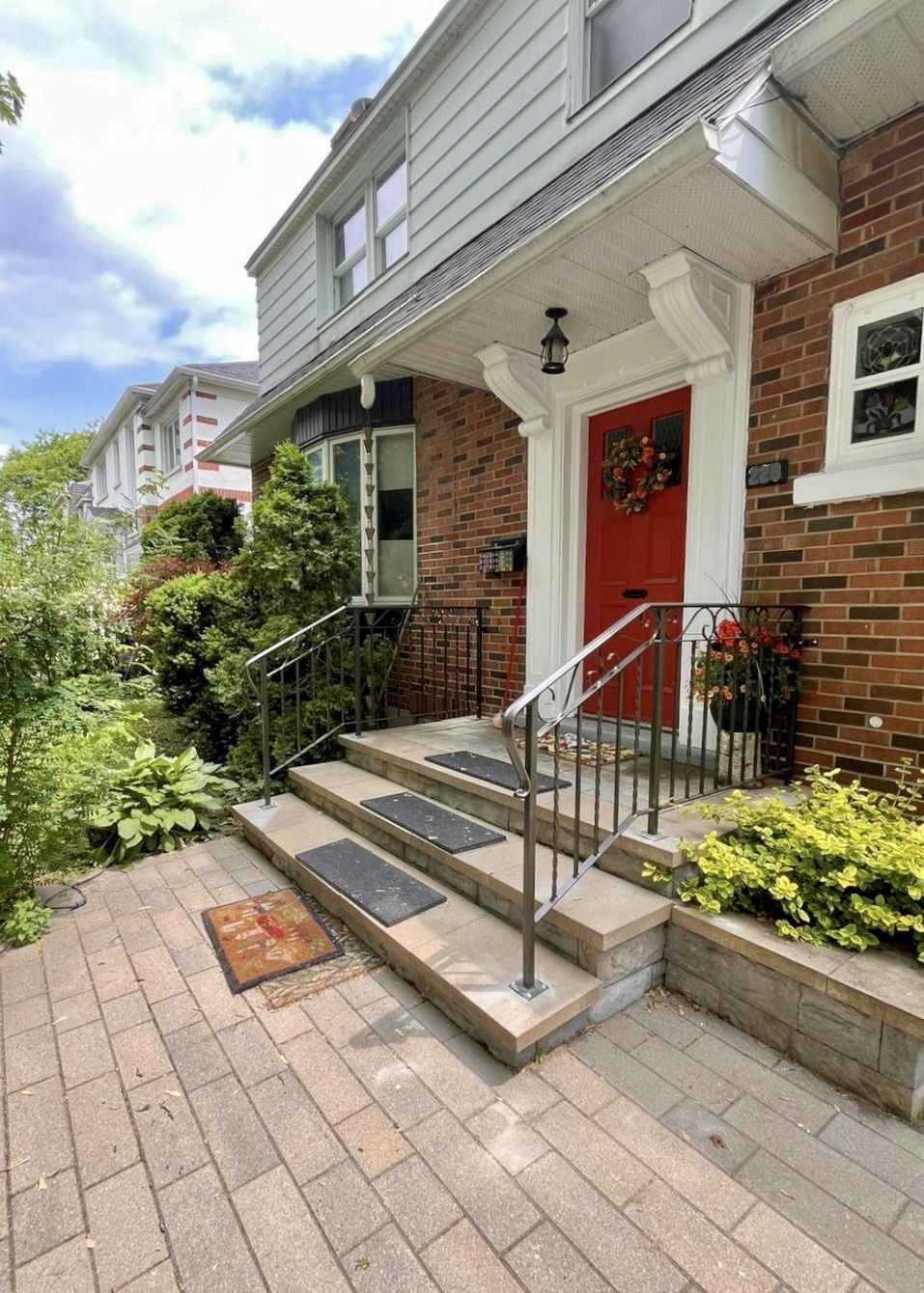 Une maison en briques avec une porte rouge et des escaliers qui y mènent.