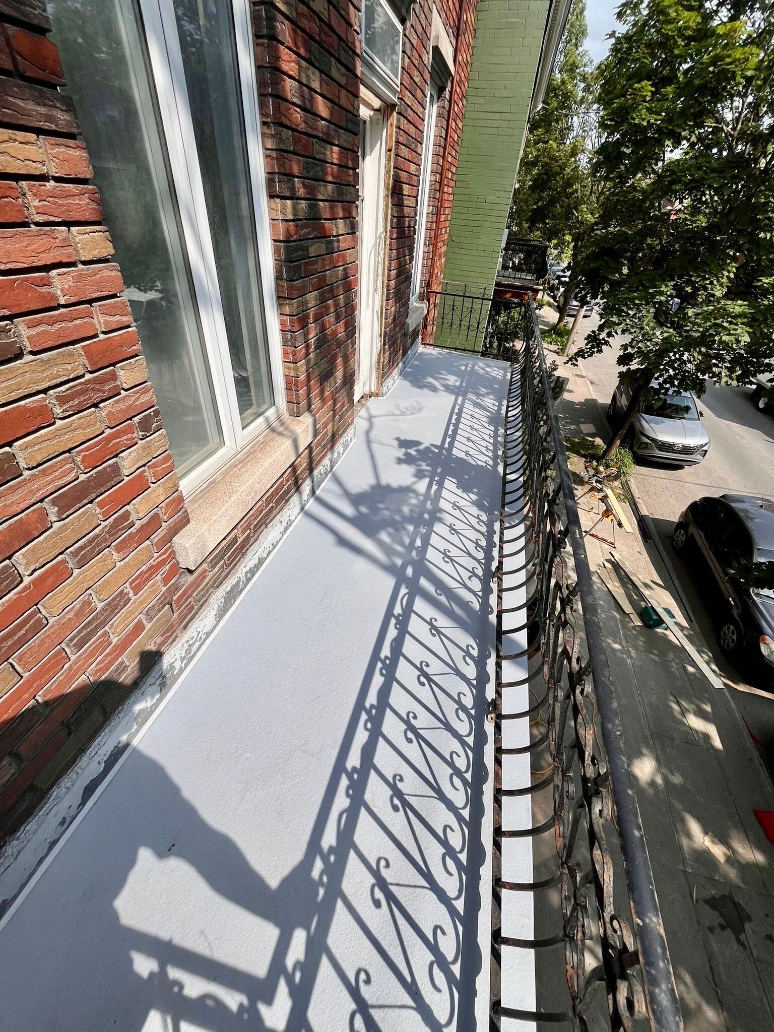 Un balcon avec une balustrade en fer forgé et un bâtiment en briques en arrière-plan.