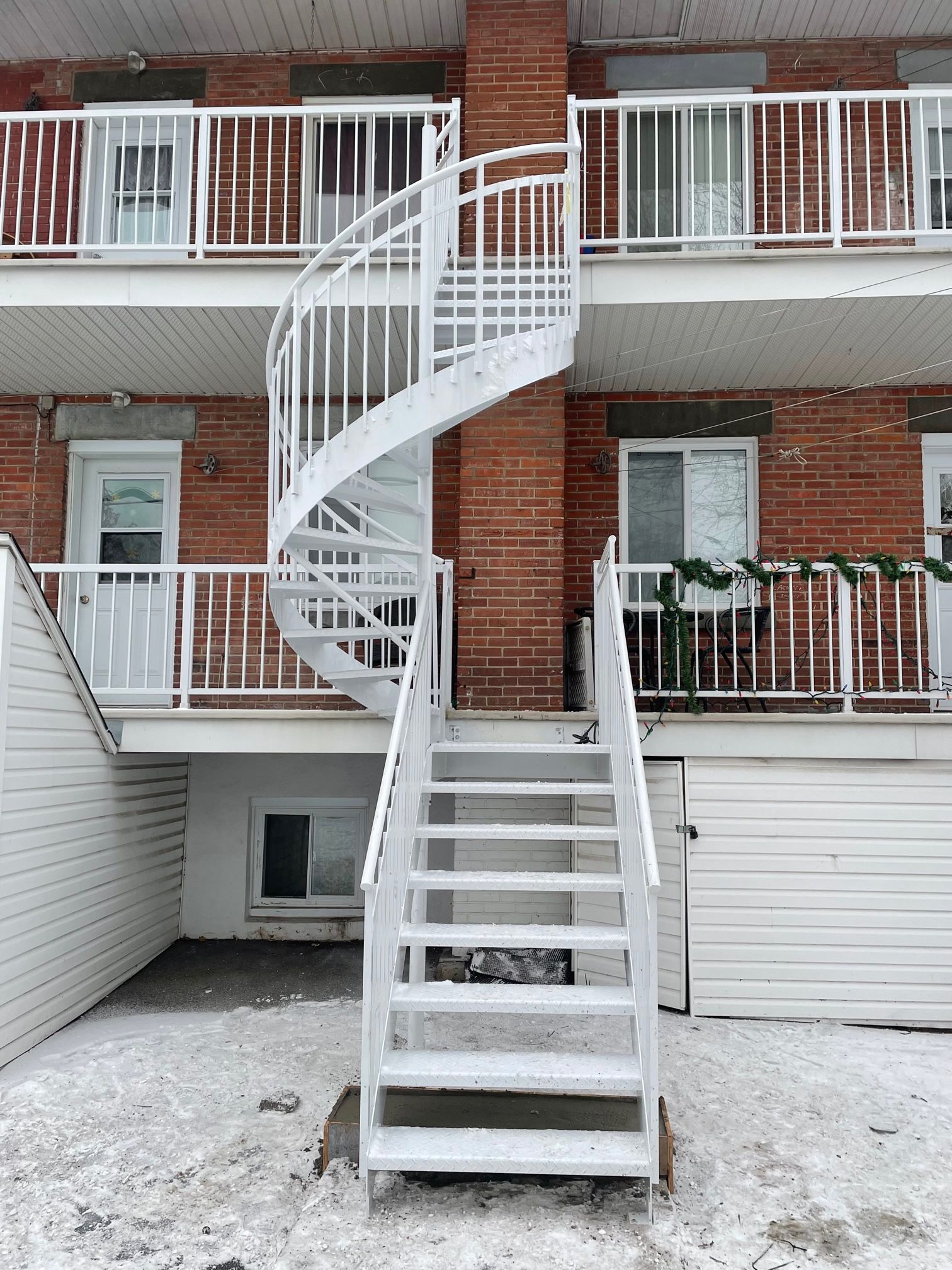 Un escalier en colimaçon mène au deuxième étage d'un immeuble en brique.