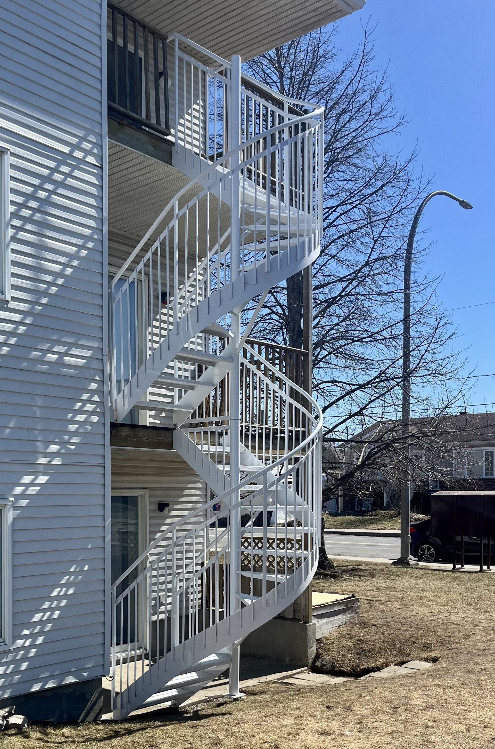 Un escalier en colimaçon blanc se trouve sur le côté d'un bâtiment.