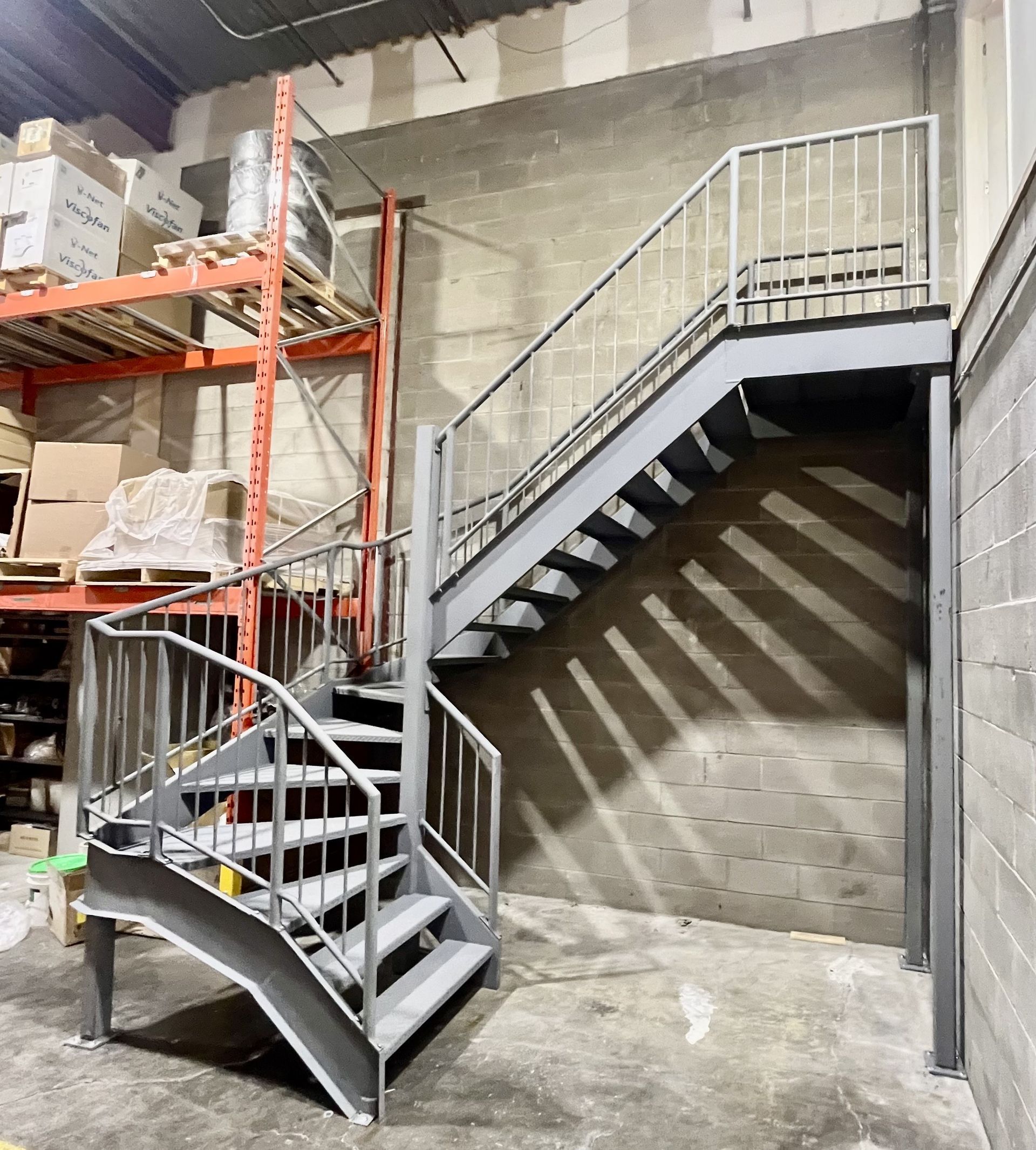 Un escalier dans un entrepôt avec des boîtes sur des étagères