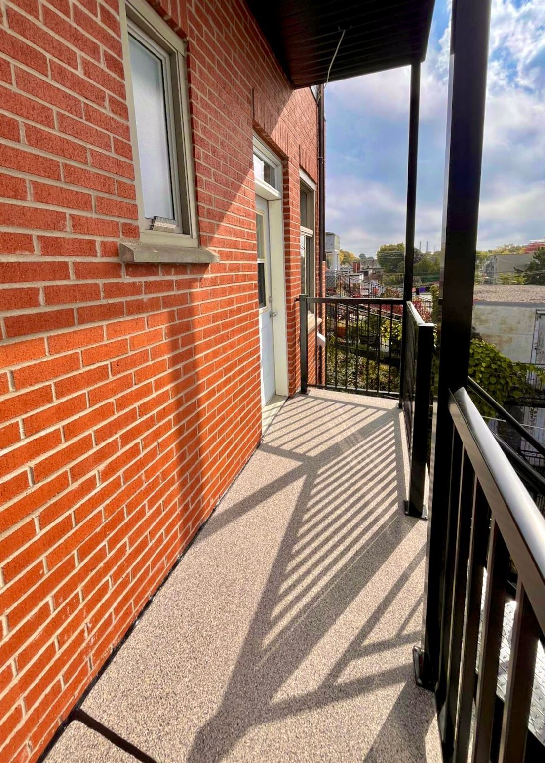 Un balcon avec un mur de briques et une fenêtre sur le côté d'un bâtiment.