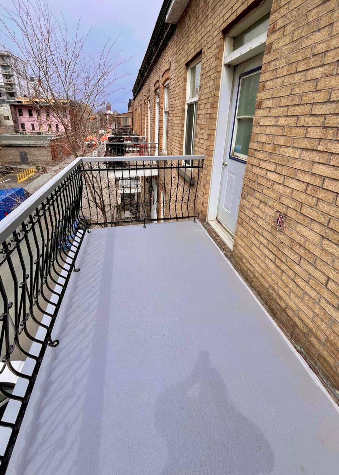 Un balcon avec une balustrade en fer forgé sur le côté d'un bâtiment en briques.