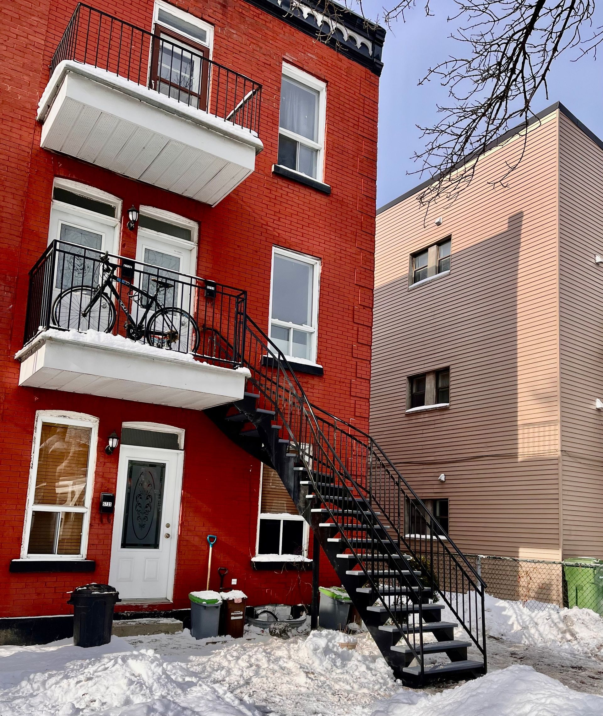 Un bâtiment en briques rouges avec des balcons et des escaliers dans la neige