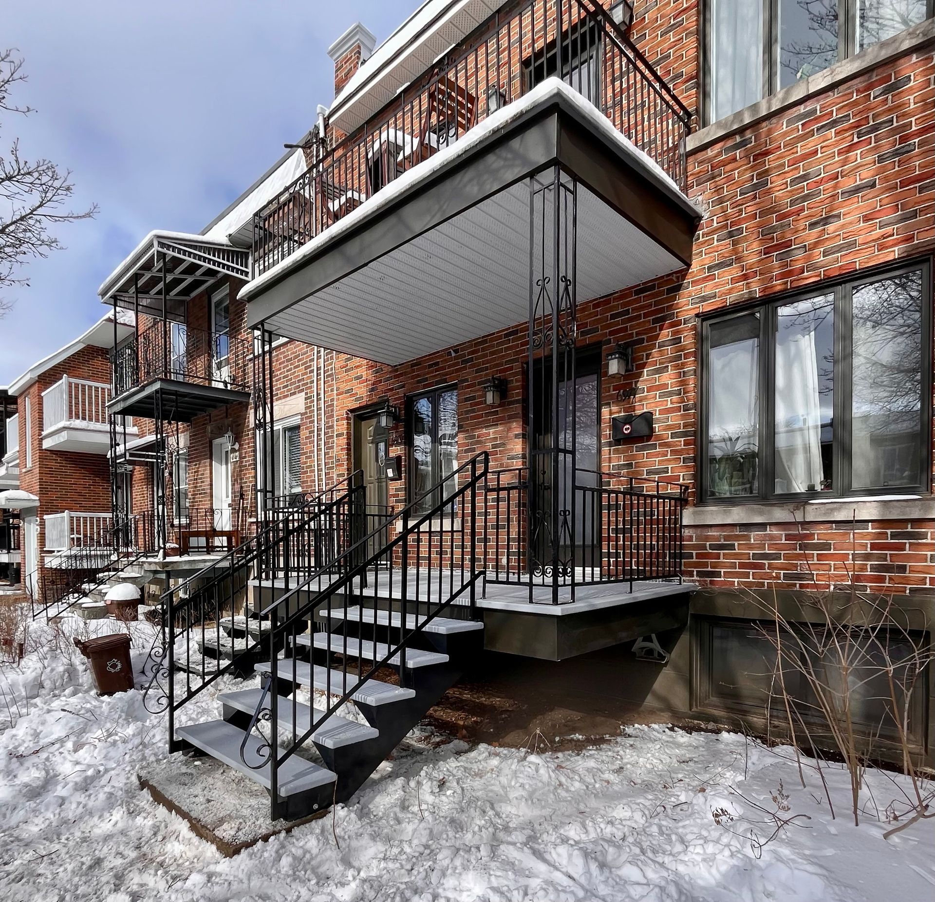 Un bâtiment en briques avec un balcon et des escaliers dans la neige