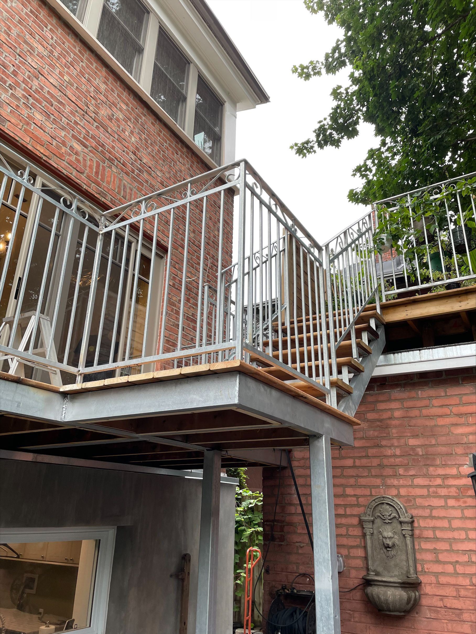 Un balcon sur le côté d'un immeuble en brique avec des escaliers qui y mènent.