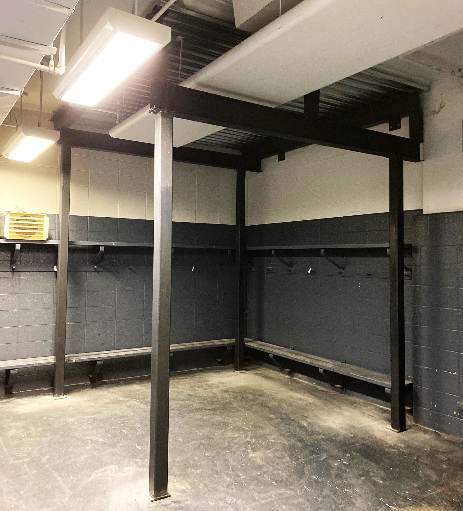 Un vestiaire vide avec des murs gris et des piliers noirs