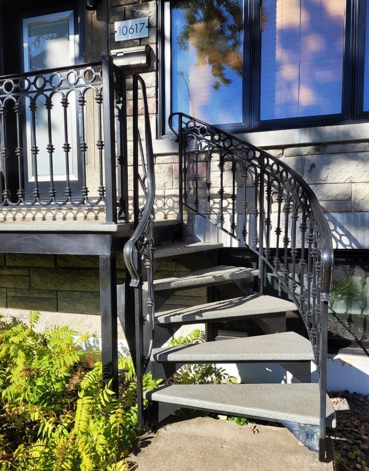 Un escalier menant à une maison avec une balustrade en fer forgé