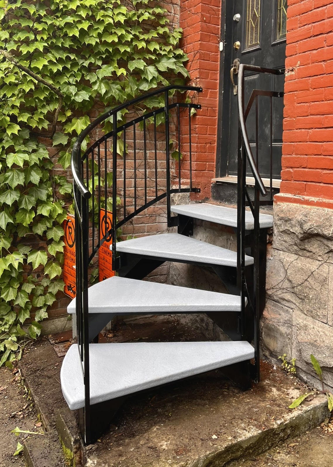 Un escalier en colimaçon se trouve devant un bâtiment en briques.