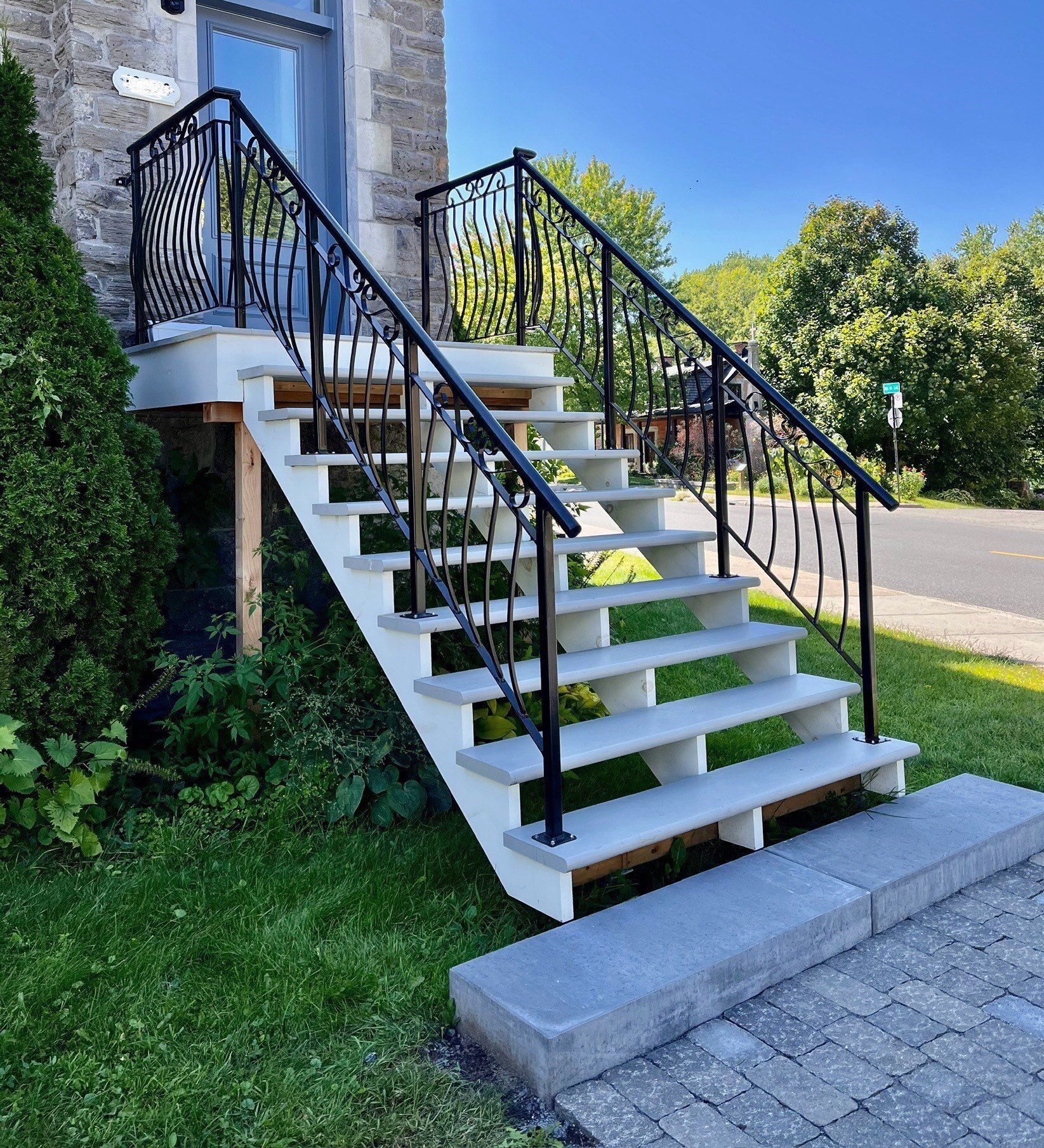 Stone staircase with black metal railings leading to a building's entrance. Green grass surrounds.
