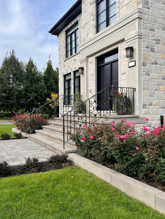 Une grande maison en pierre avec des escaliers et des fleurs devant.