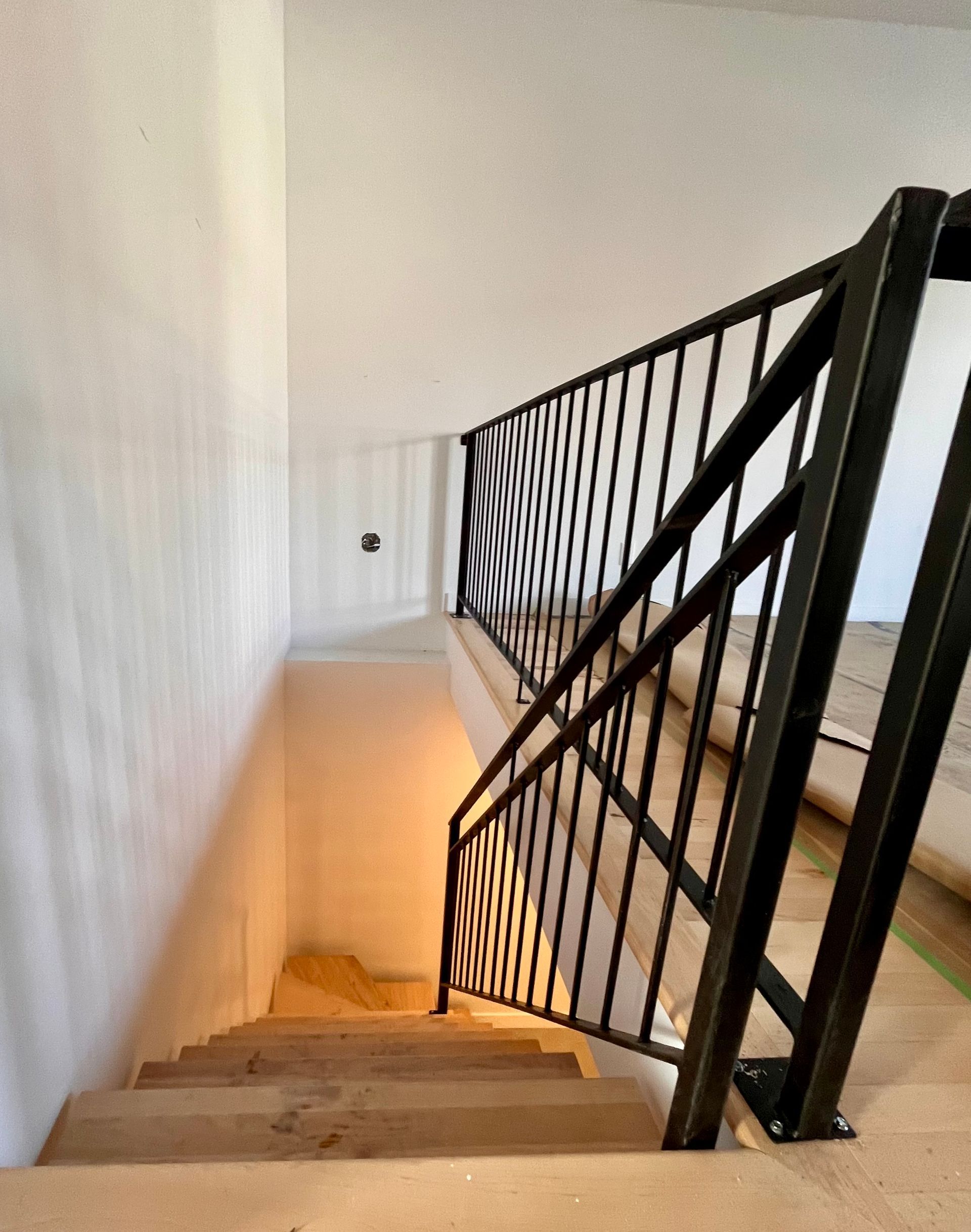 Un escalier avec une rampe métallique montant au deuxième étage