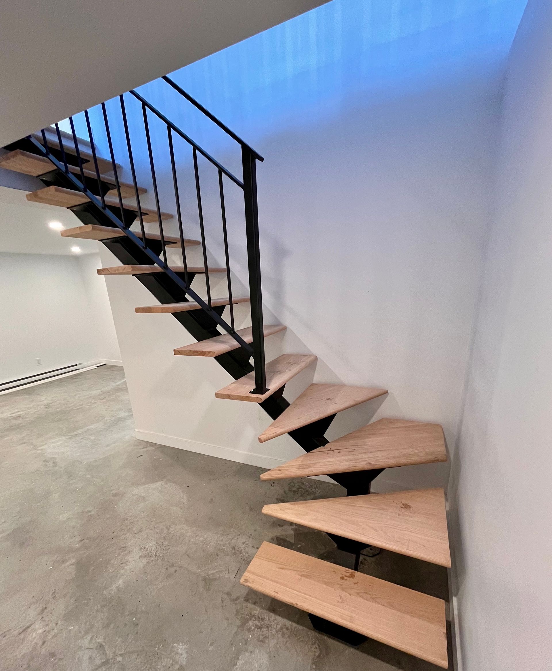 Un escalier en bois avec une rampe en métal dans une pièce vide