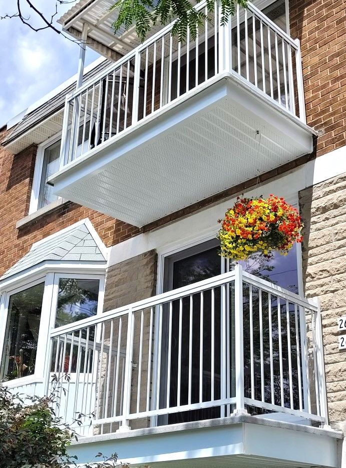 Un balcon avec des fleurs suspendues sur un bâtiment en brique