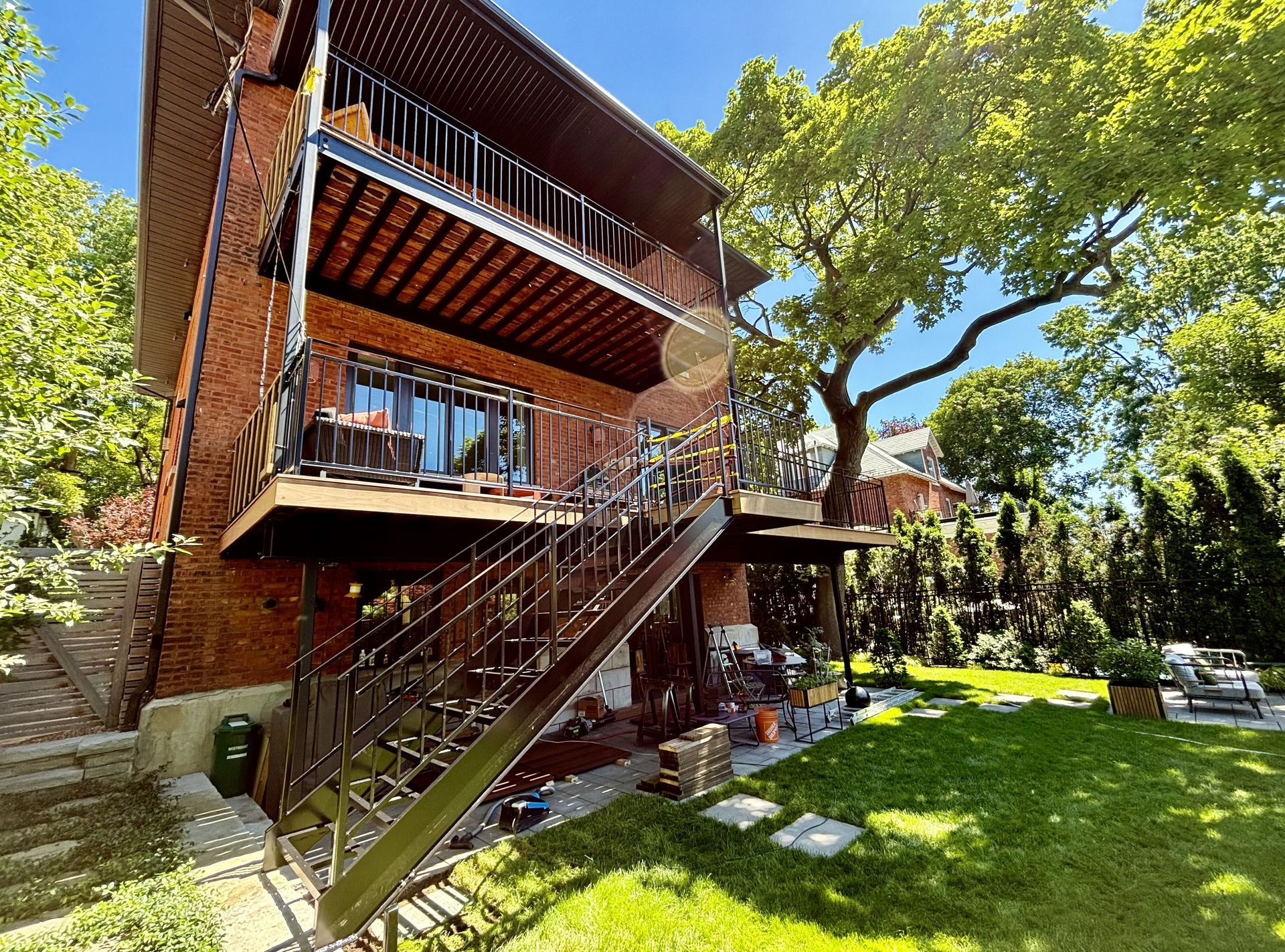 Une grande maison en brique avec une terrasse et des escaliers dans la cour.