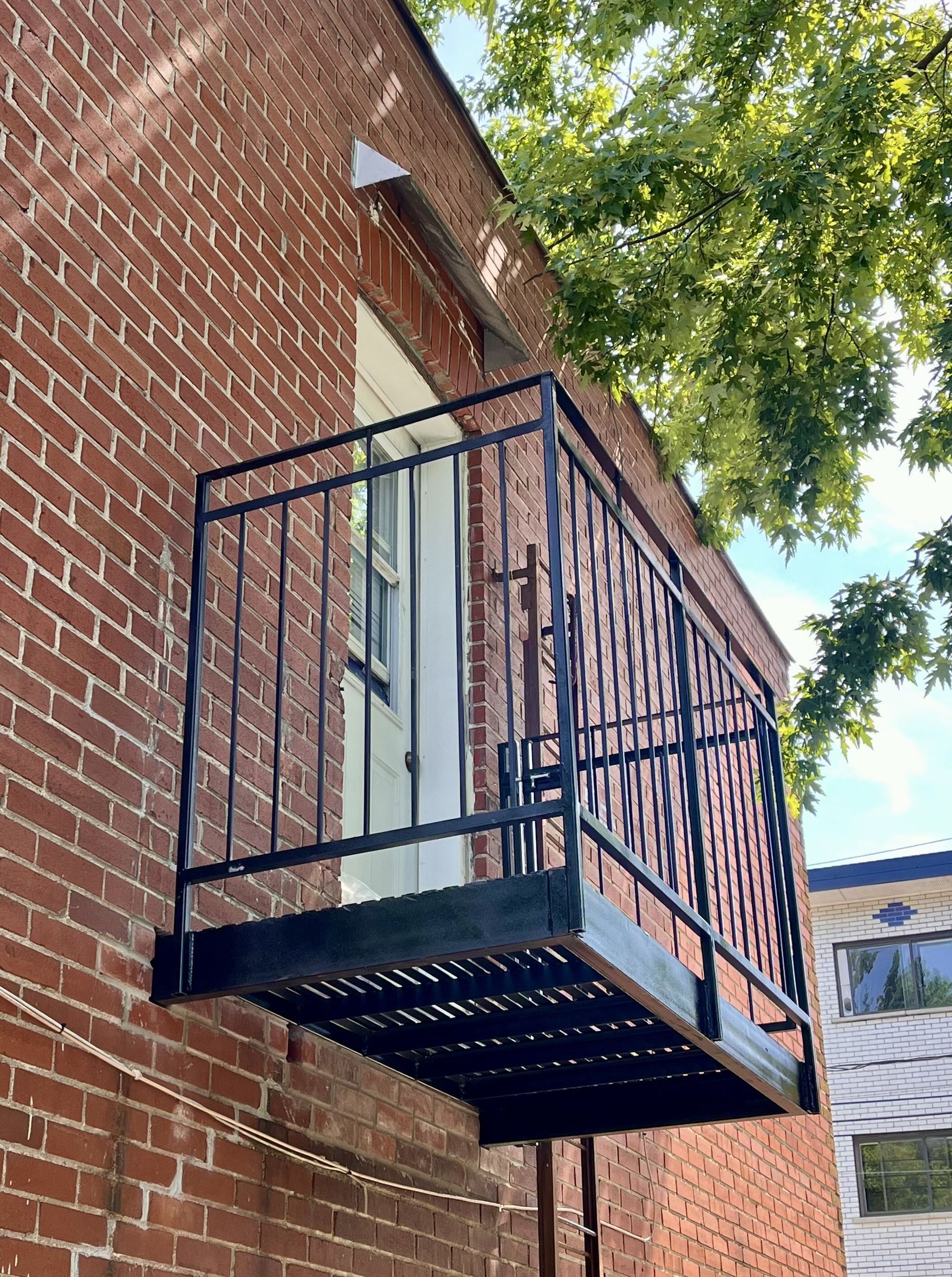 Une issue de secours est fixée sur le côté d'un bâtiment en brique.