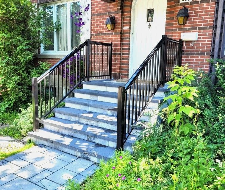 Une maison en brique avec des escaliers et une balustrade noire