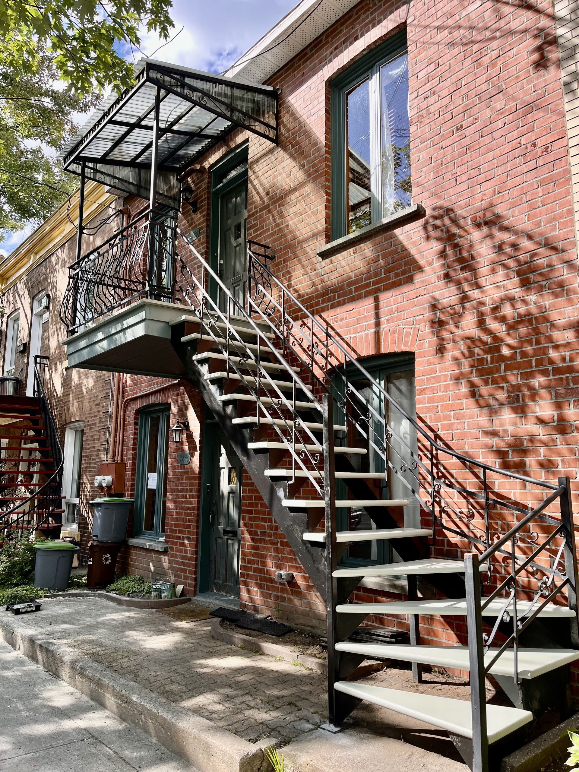 Un bâtiment en brique avec des escaliers qui y mènent et un balcon.