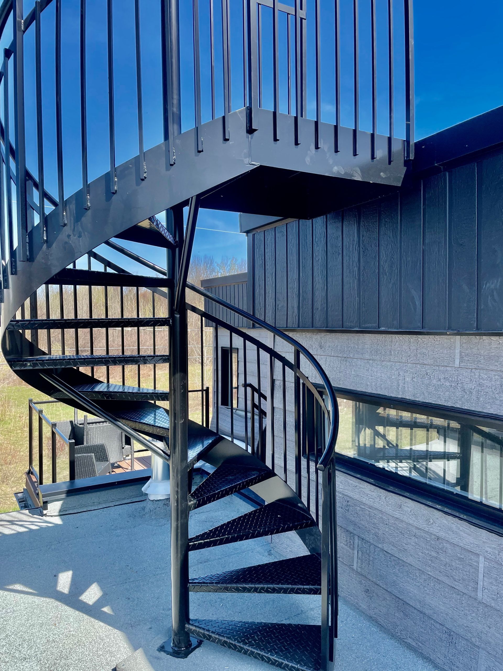 Un escalier en colimaçon menant à un bâtiment avec un ciel bleu en arrière-plan.
