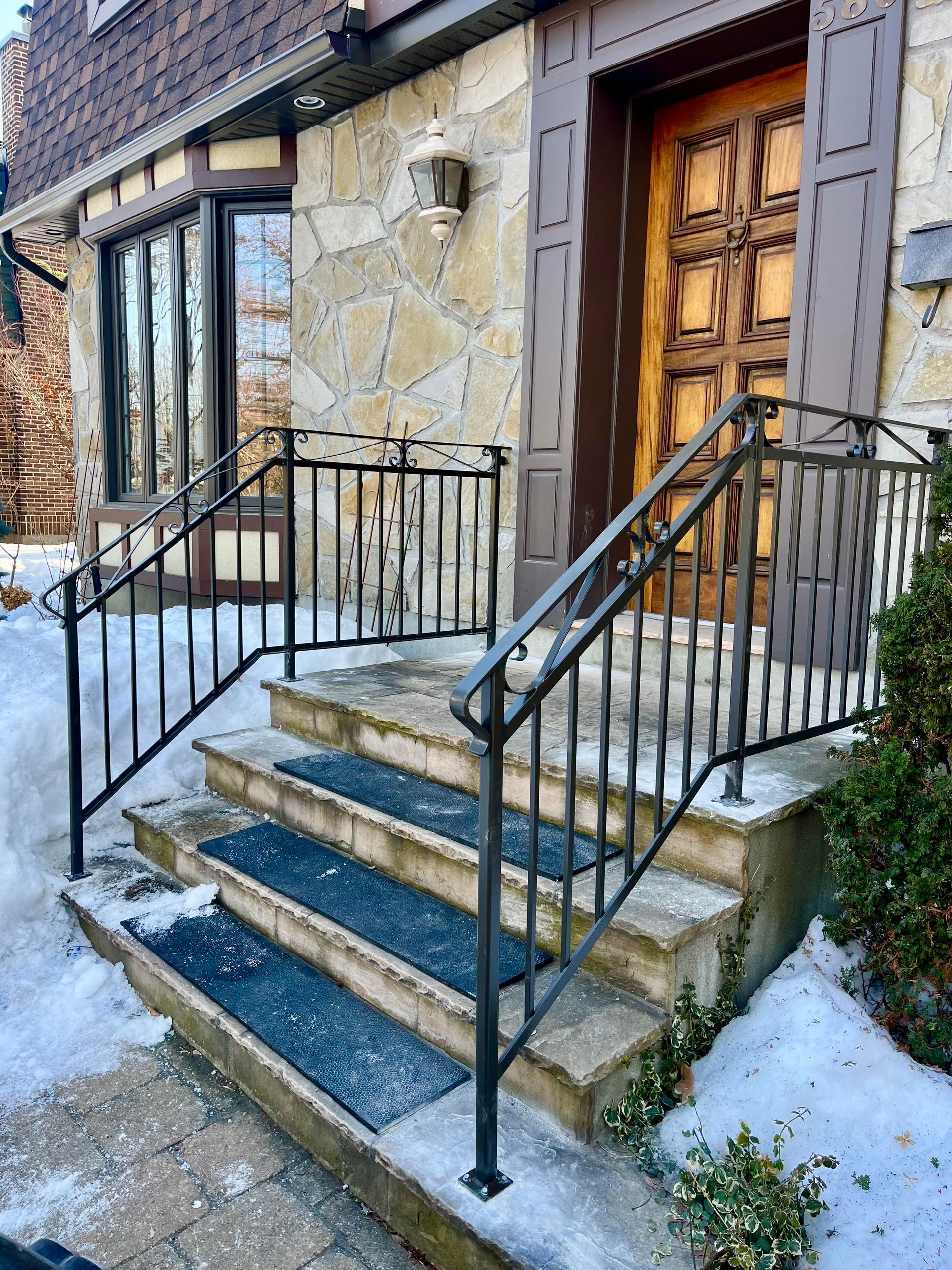 Un bâtiment en pierre avec un escalier et une rampe en fer forgé.