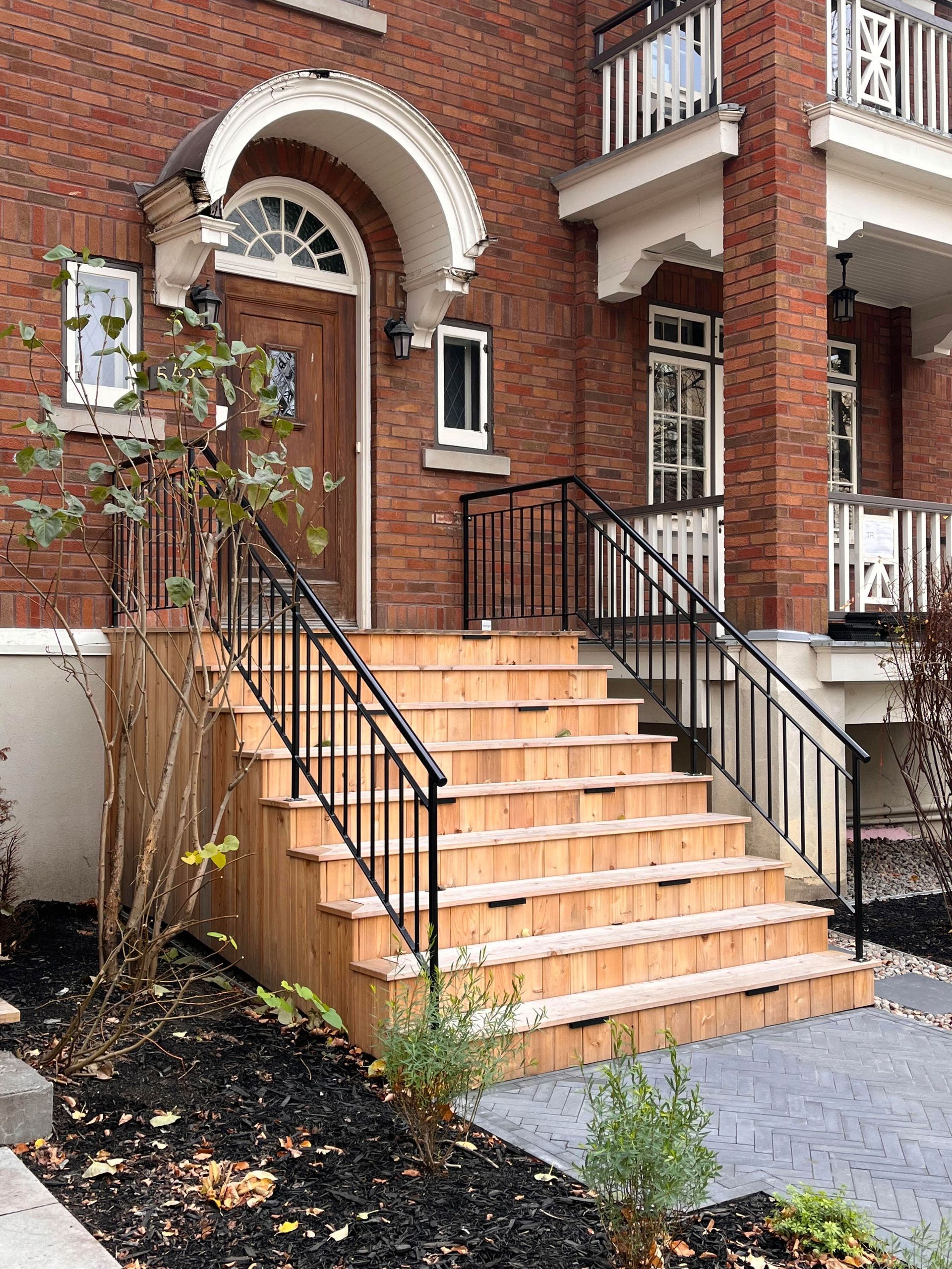 Un bâtiment en briques avec des escaliers en bois menant à la porte d'entrée.