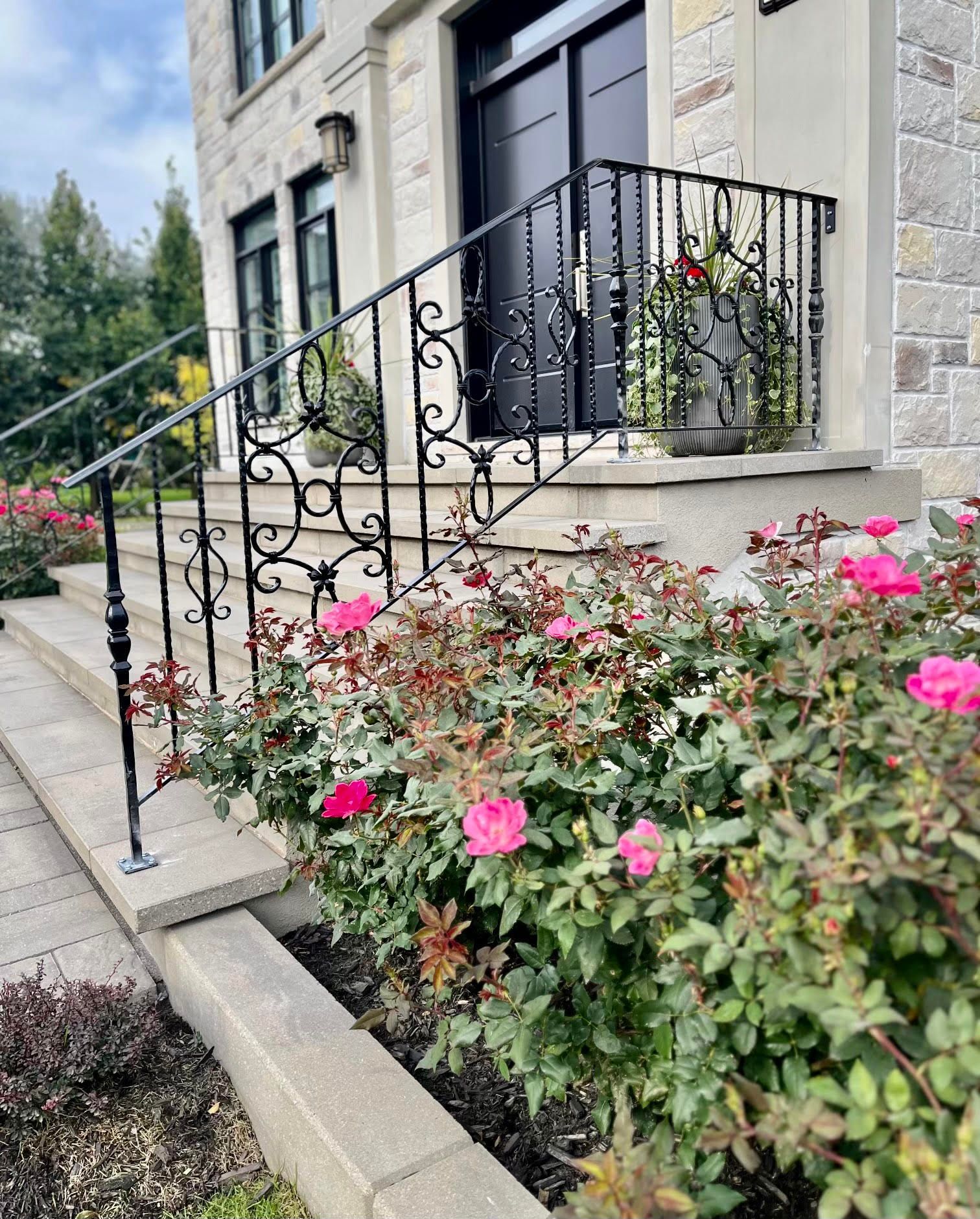 Une maison avec une balustrade en fer forgé et des fleurs devant.