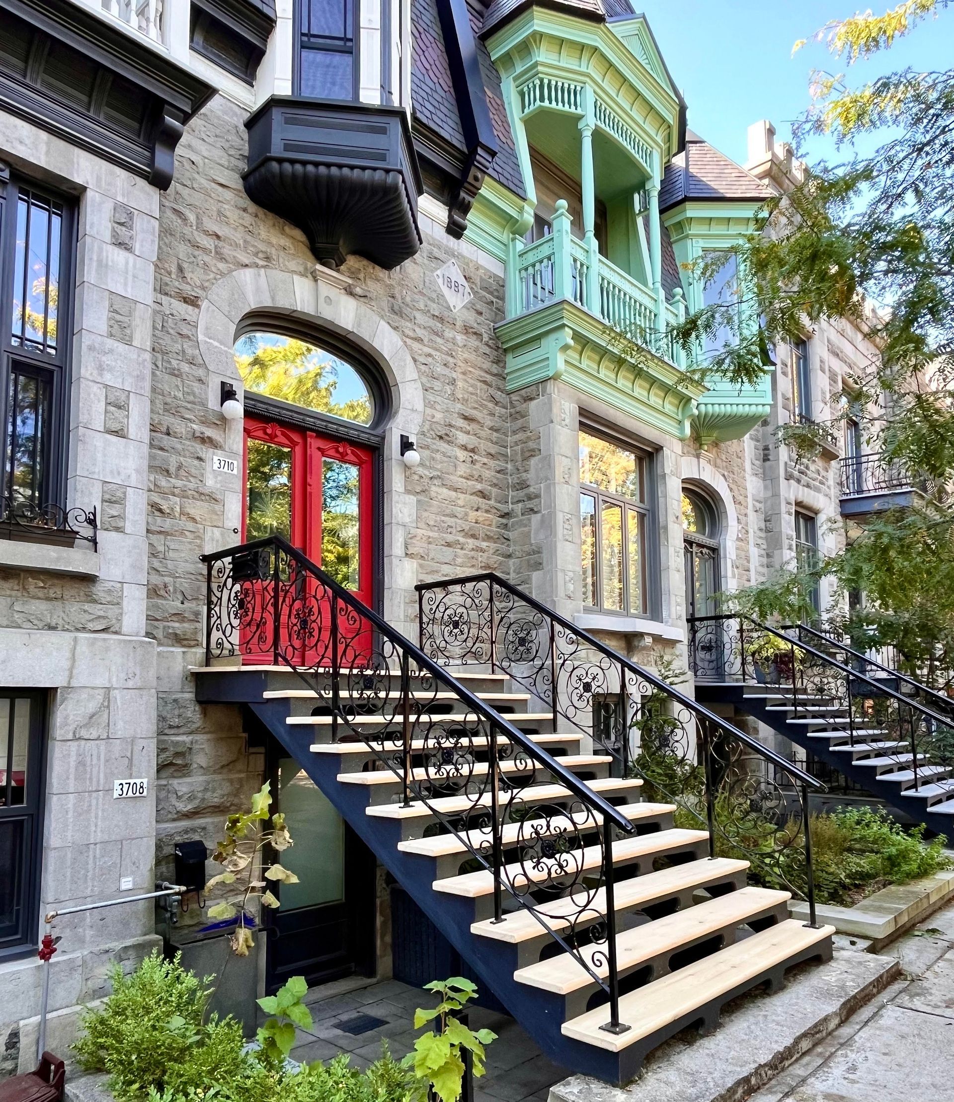 Un bâtiment avec des escaliers qui y mènent et une porte rouge.