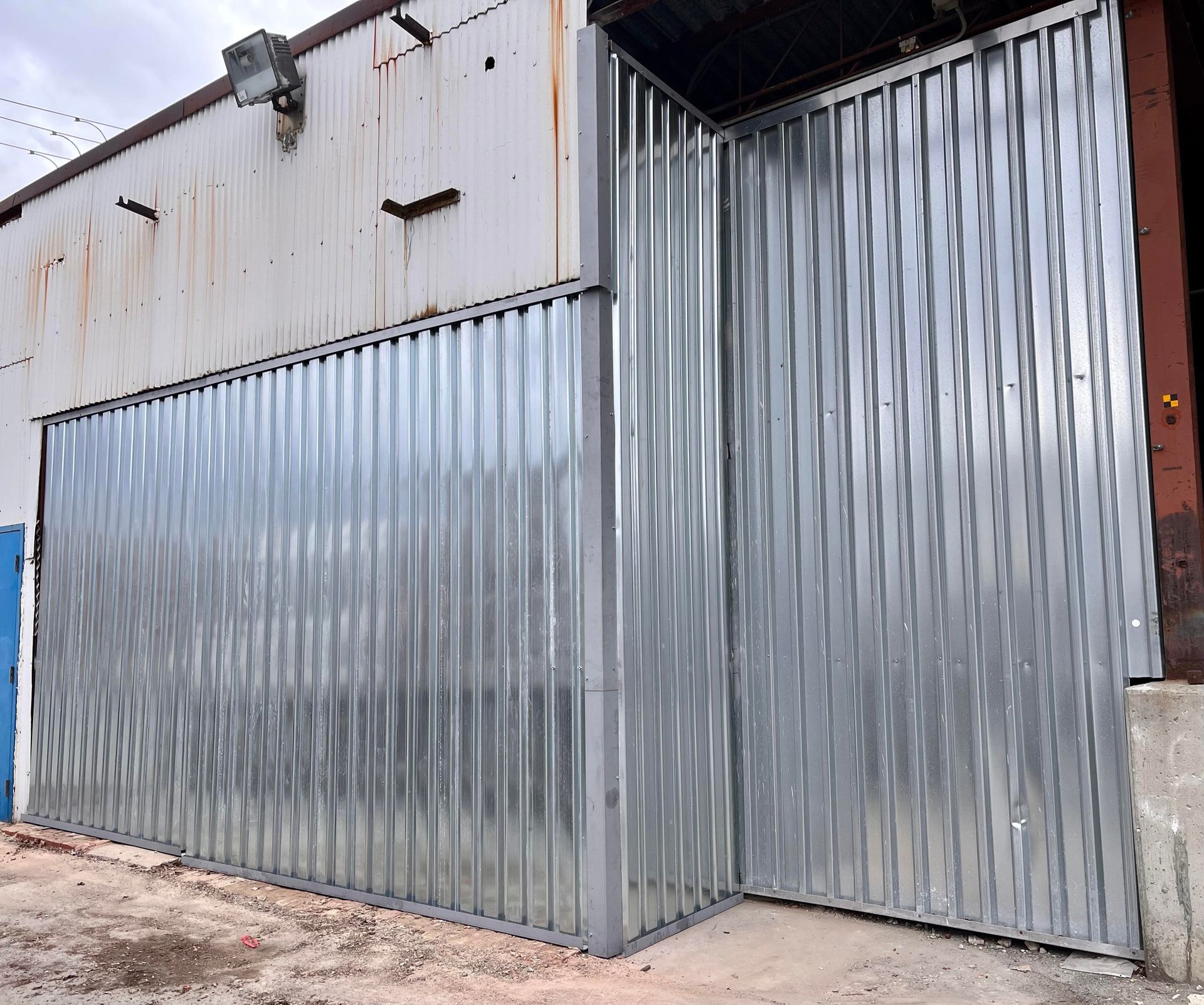 Une grande clôture métallique se trouve devant un bâtiment