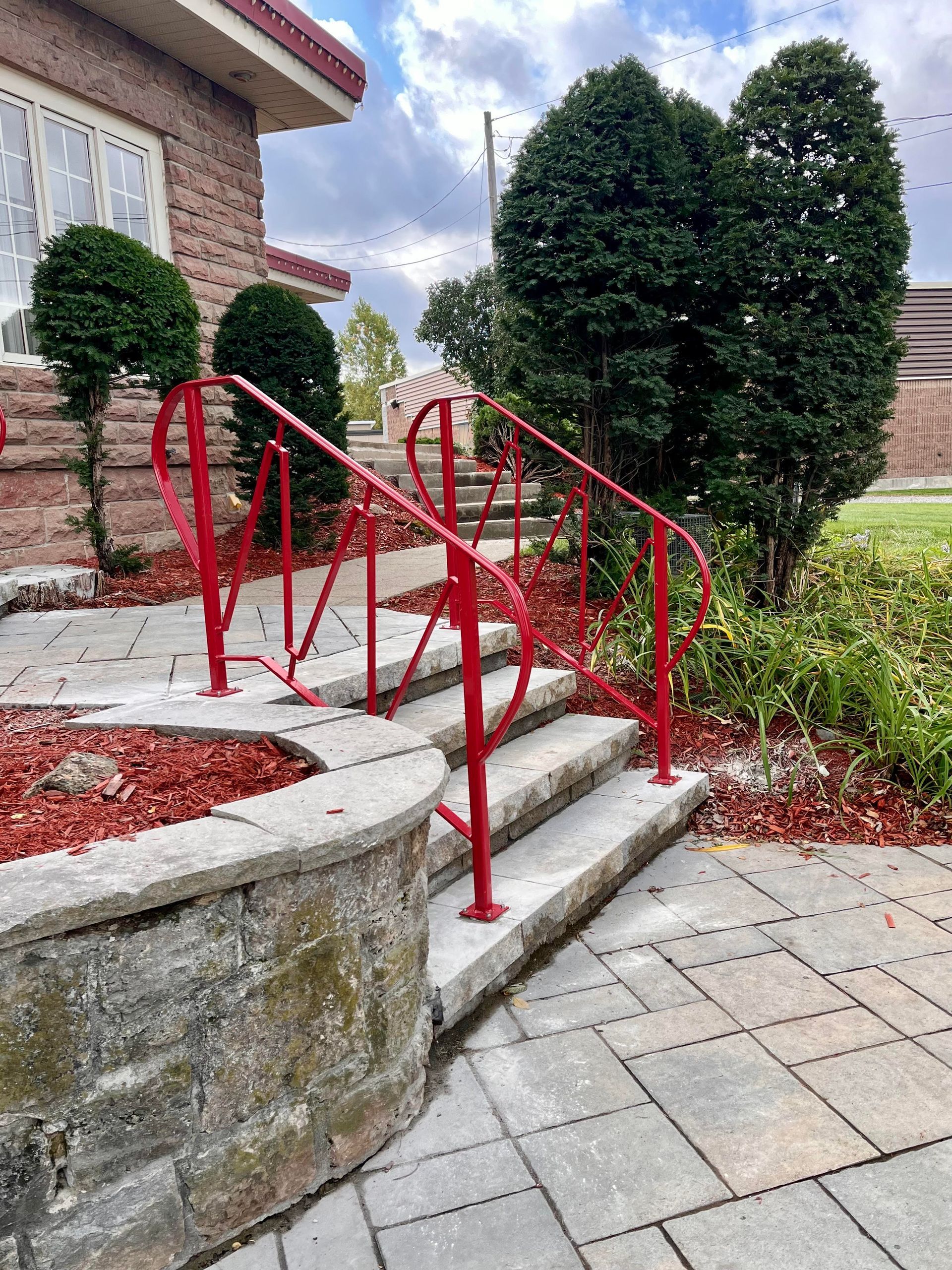 Une balustrade rouge sur un escalier devant une maison.