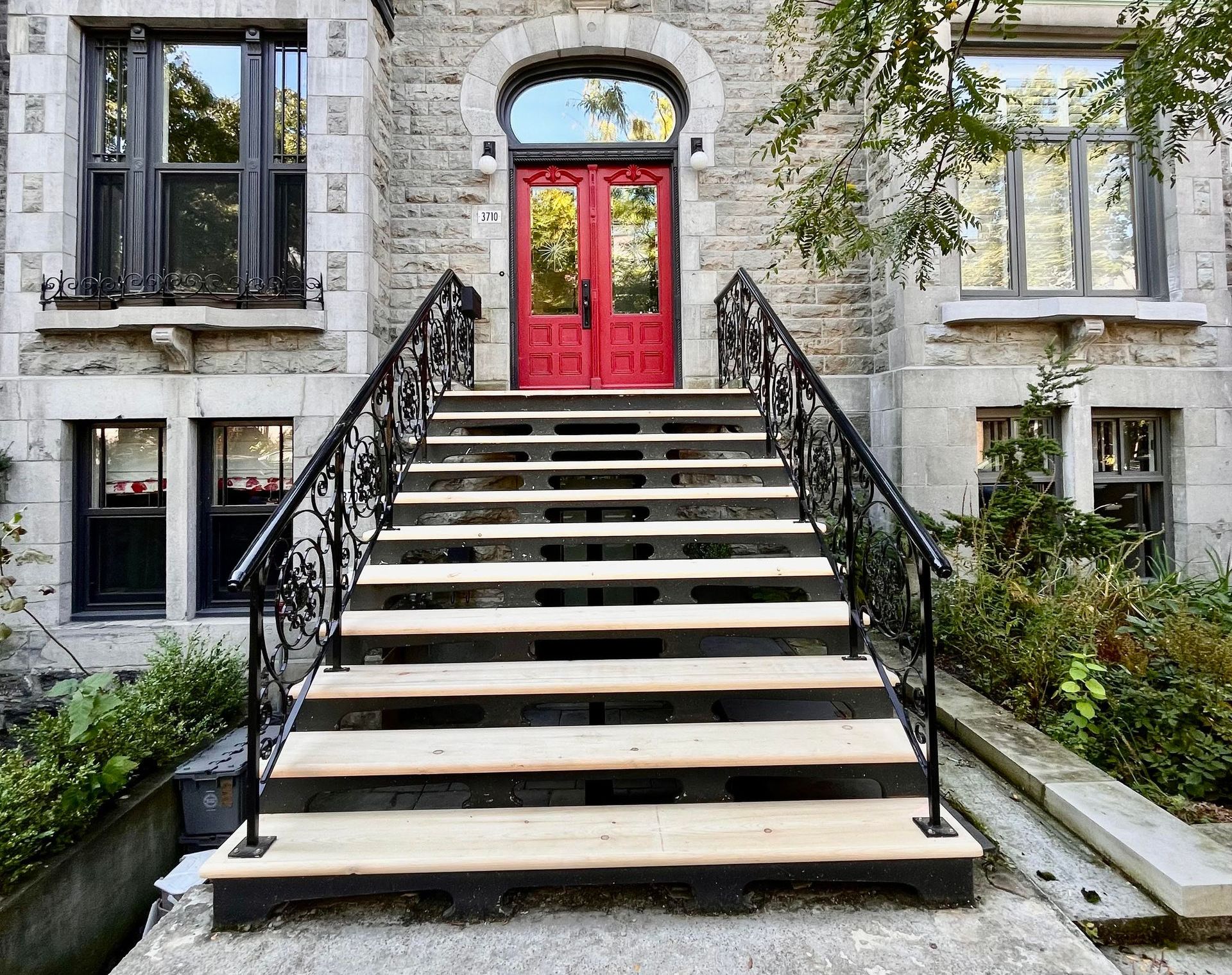 Un ensemble d'escaliers en bois menant à une porte rouge d'un bâtiment.
