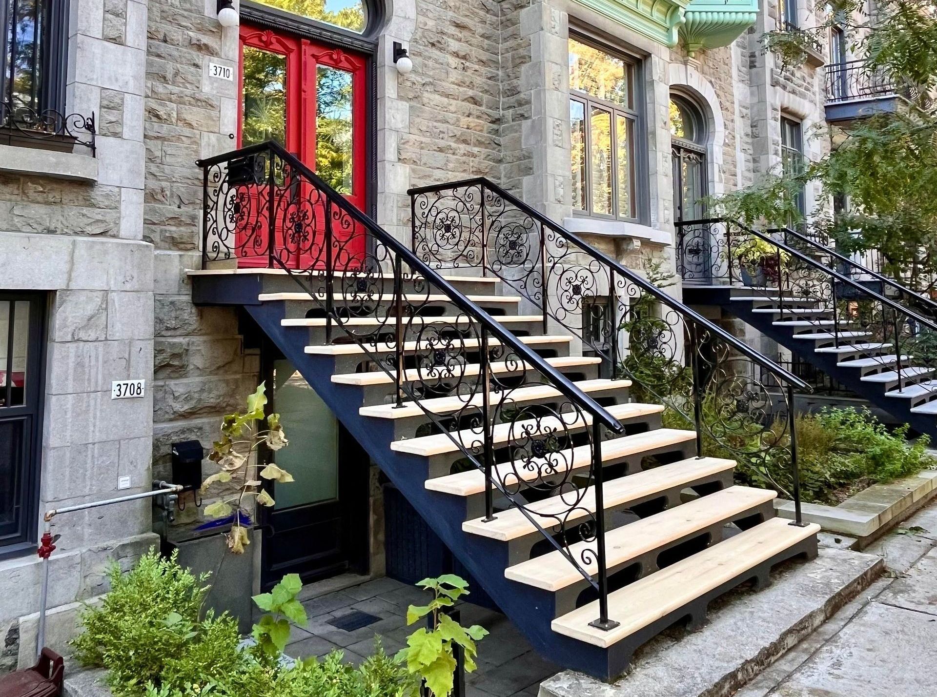 Un escalier menant à un bâtiment en pierre avec une porte rouge.