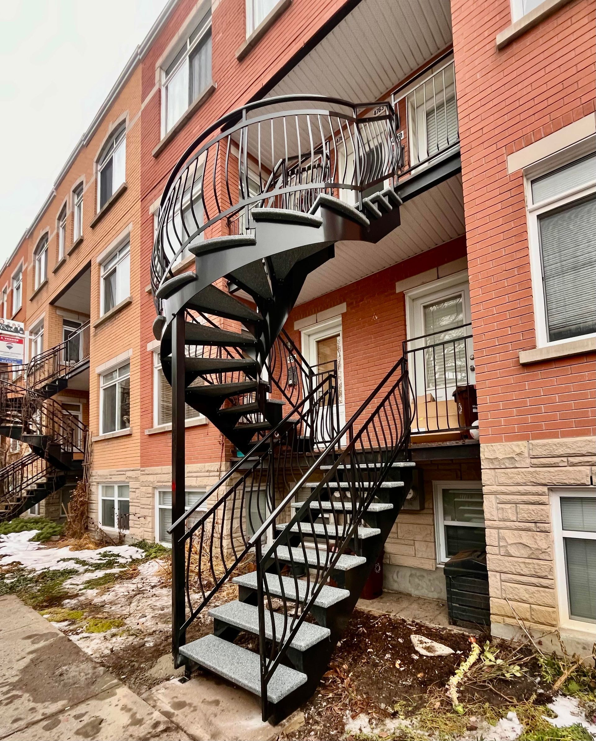 Un escalier en colimaçon se trouve à l'extérieur d'un bâtiment en brique.