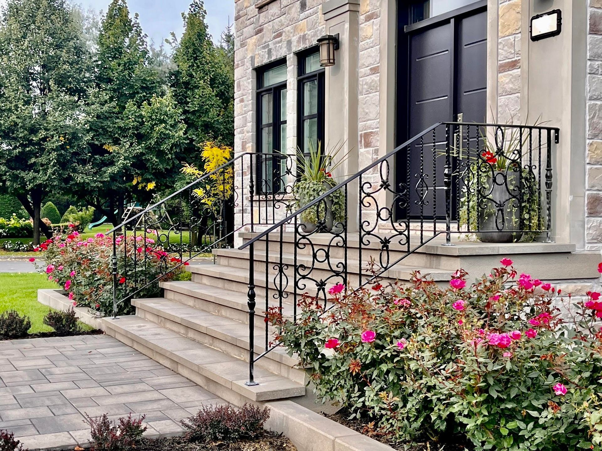 La façade d'une maison avec des escaliers et des fleurs devant elle.