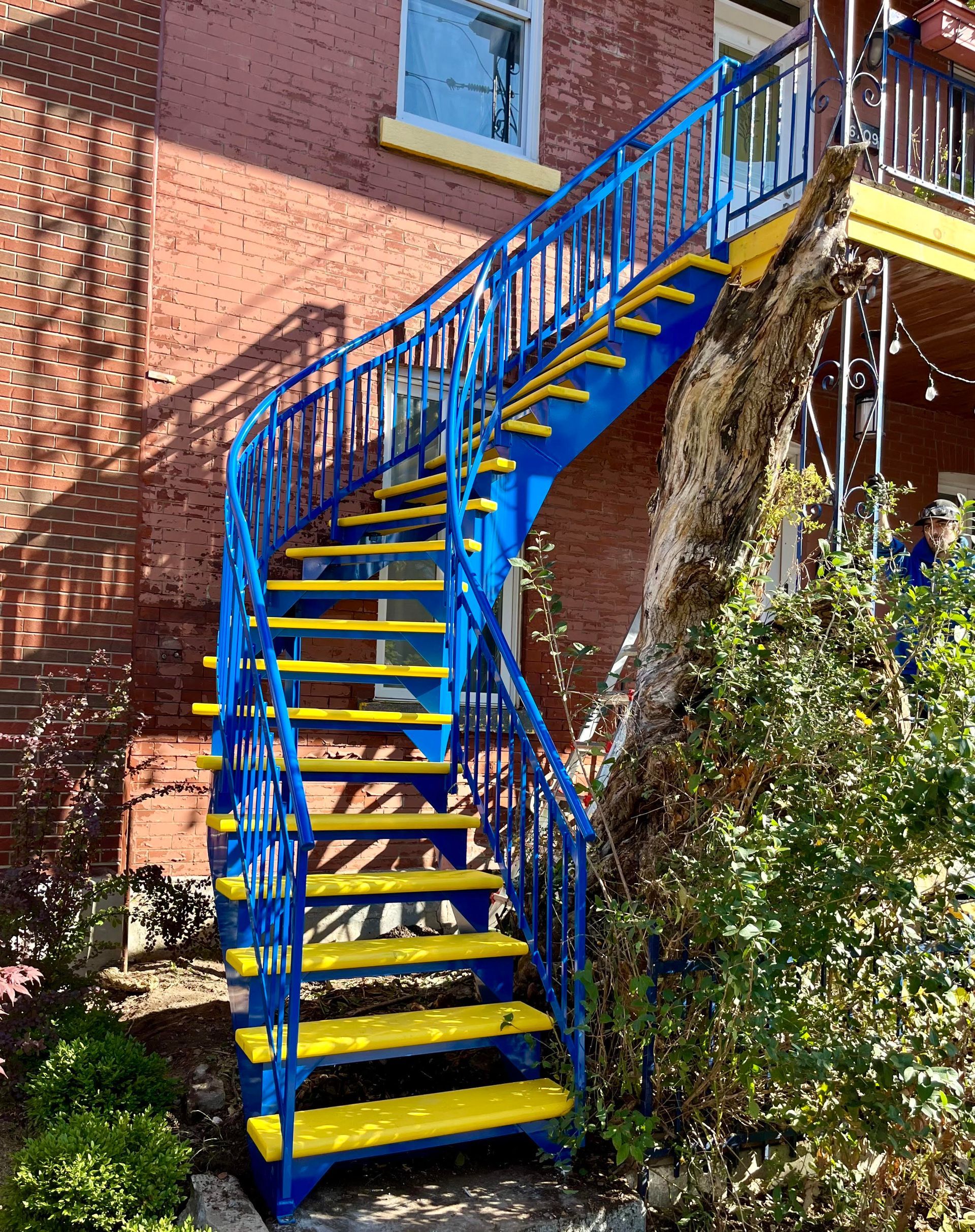 Un escalier bleu et jaune menant à un bâtiment en briques.