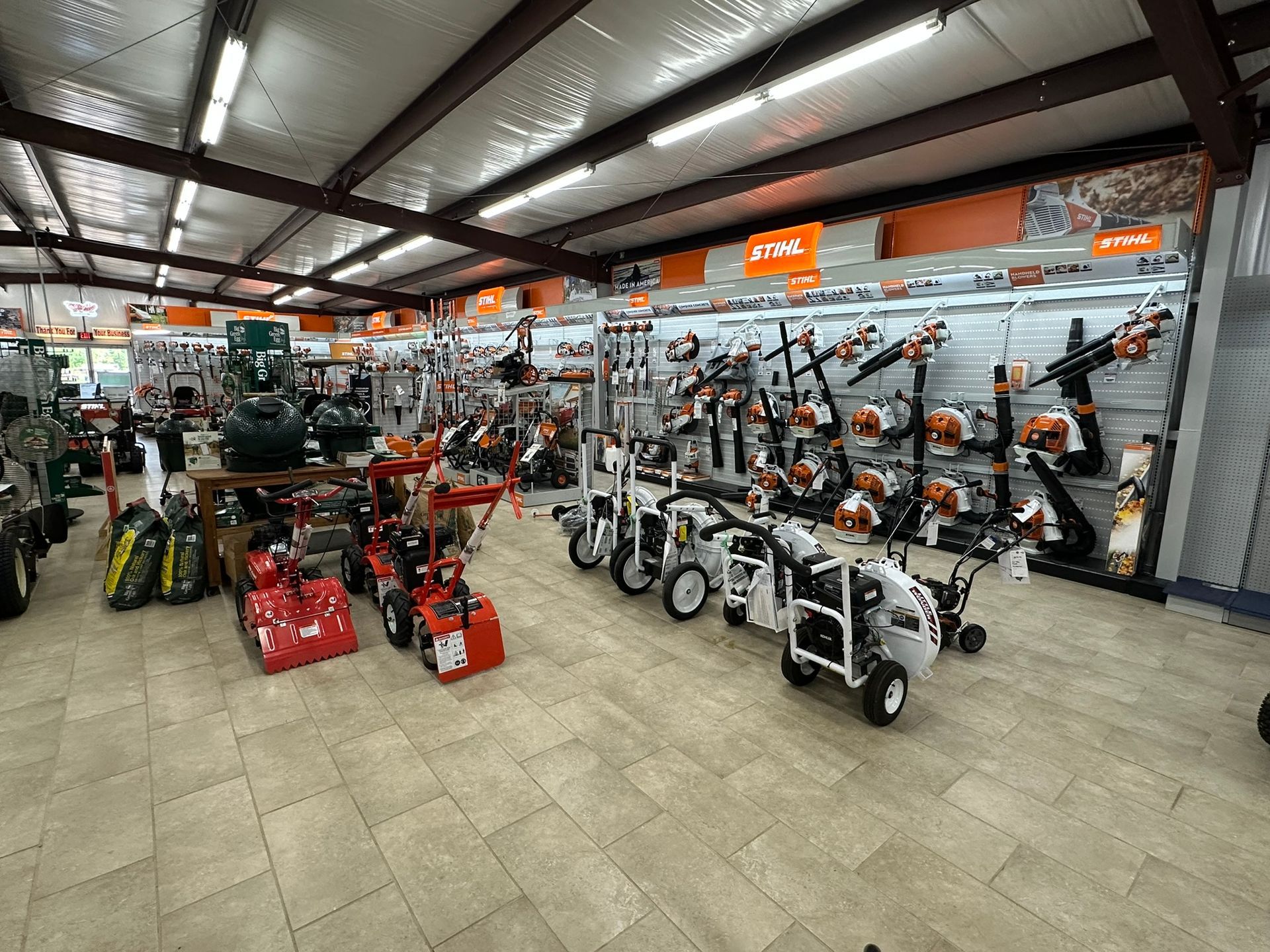 A large room filled with lots of lawn mower and blower equipment.