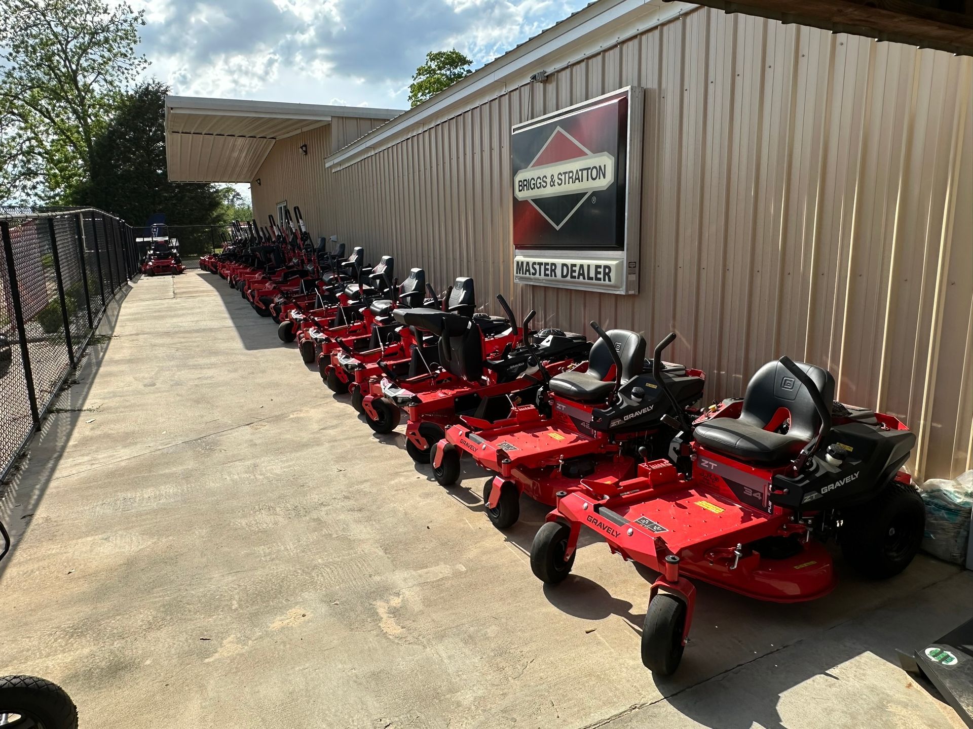 A row of red lawn mowers are parked in front of a building.